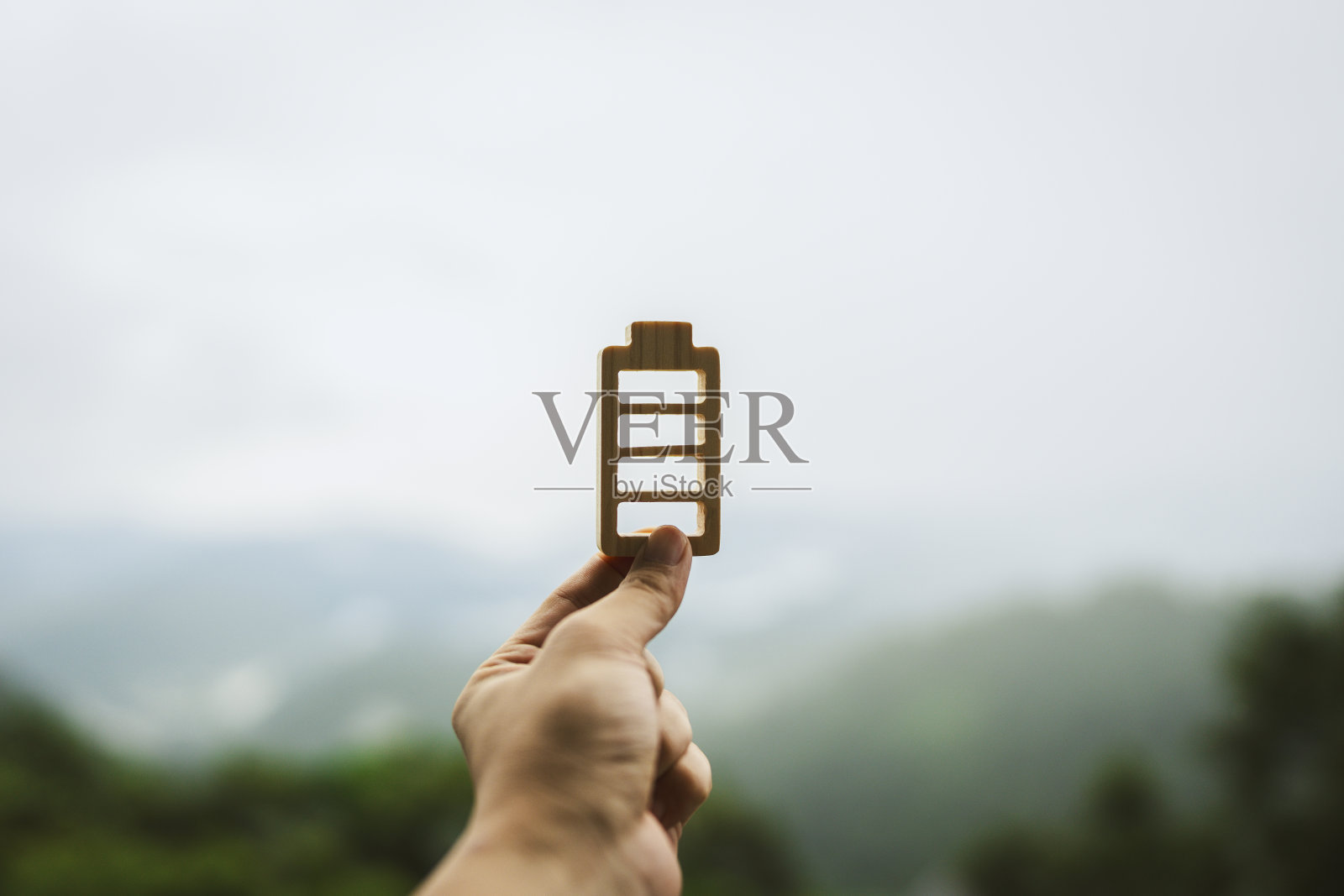 商人拿着电池模型,商人去山上旅行,为工作充电,对成功的态度,机遇,未来的商业趋势和工作与生活的平衡。照片摄影图片