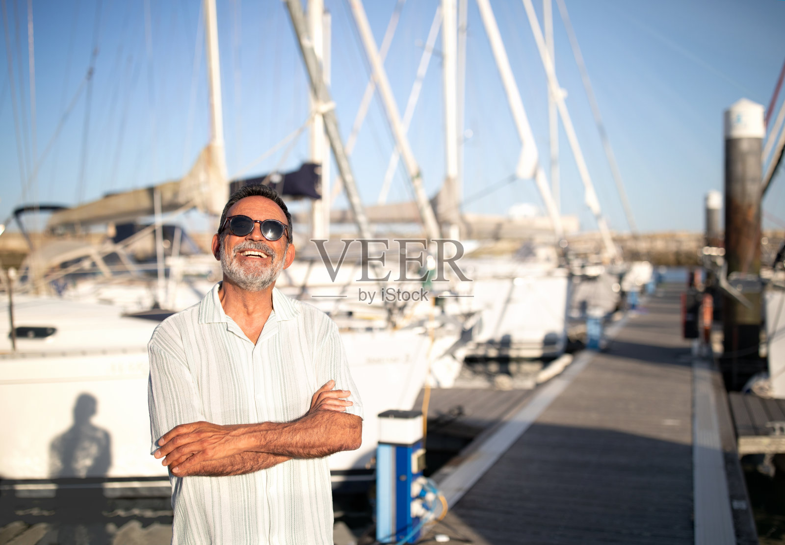 快乐的成熟男子在游艇附近摆姿势照片摄影图片