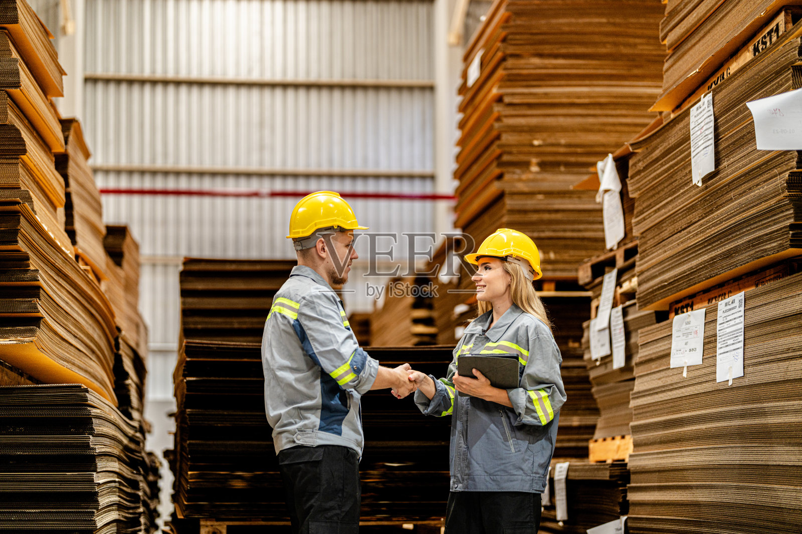 一男一女工人边走边检查货物,准备发货。女工视察商店工厂。物流员工在现场仓库区拿着文件夹准备运输。照片摄影图片