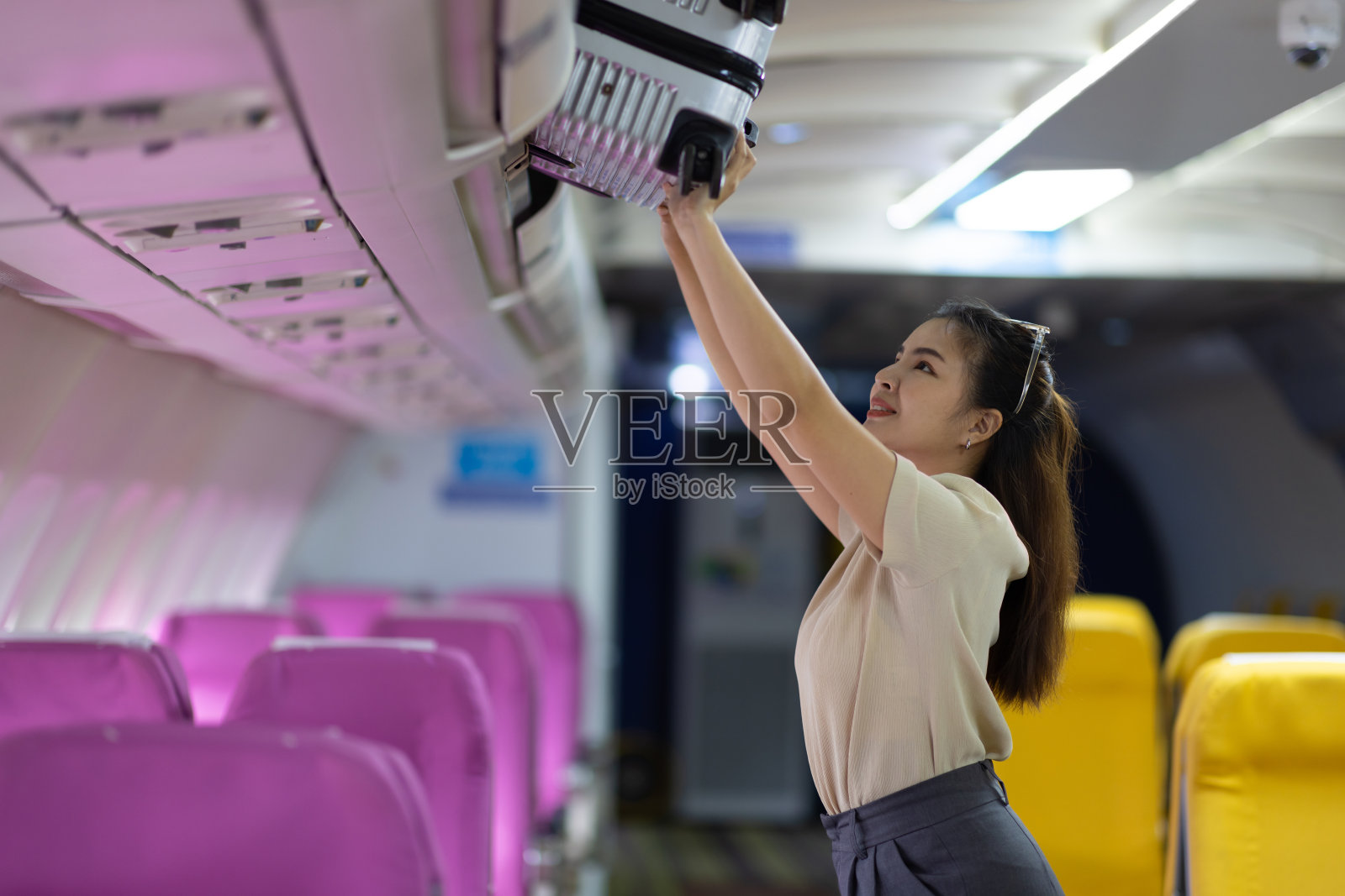 女游客在飞机舱内收拾行李。照片摄影图片