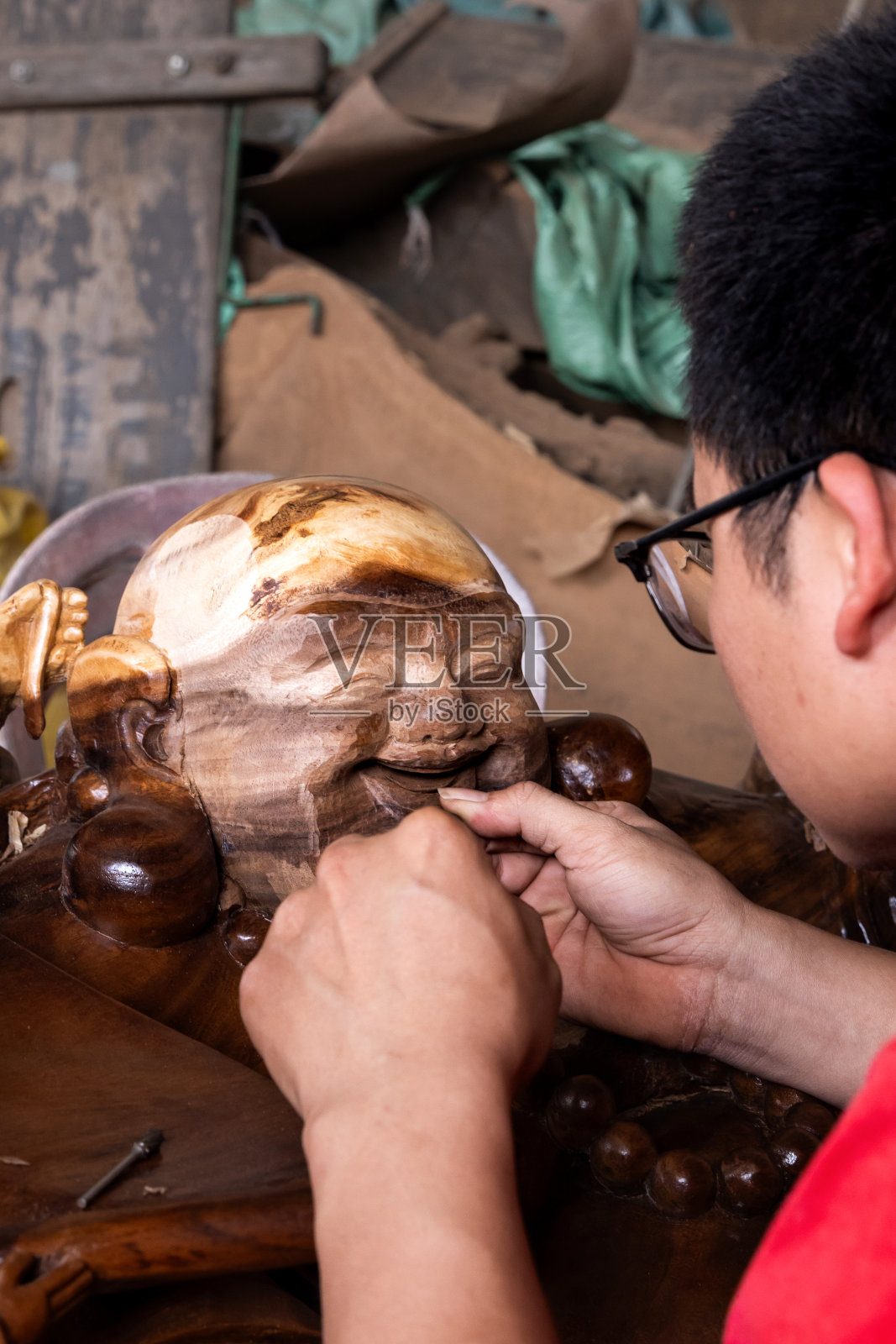 一名男子雕刻木佛的头部。照片摄影图片