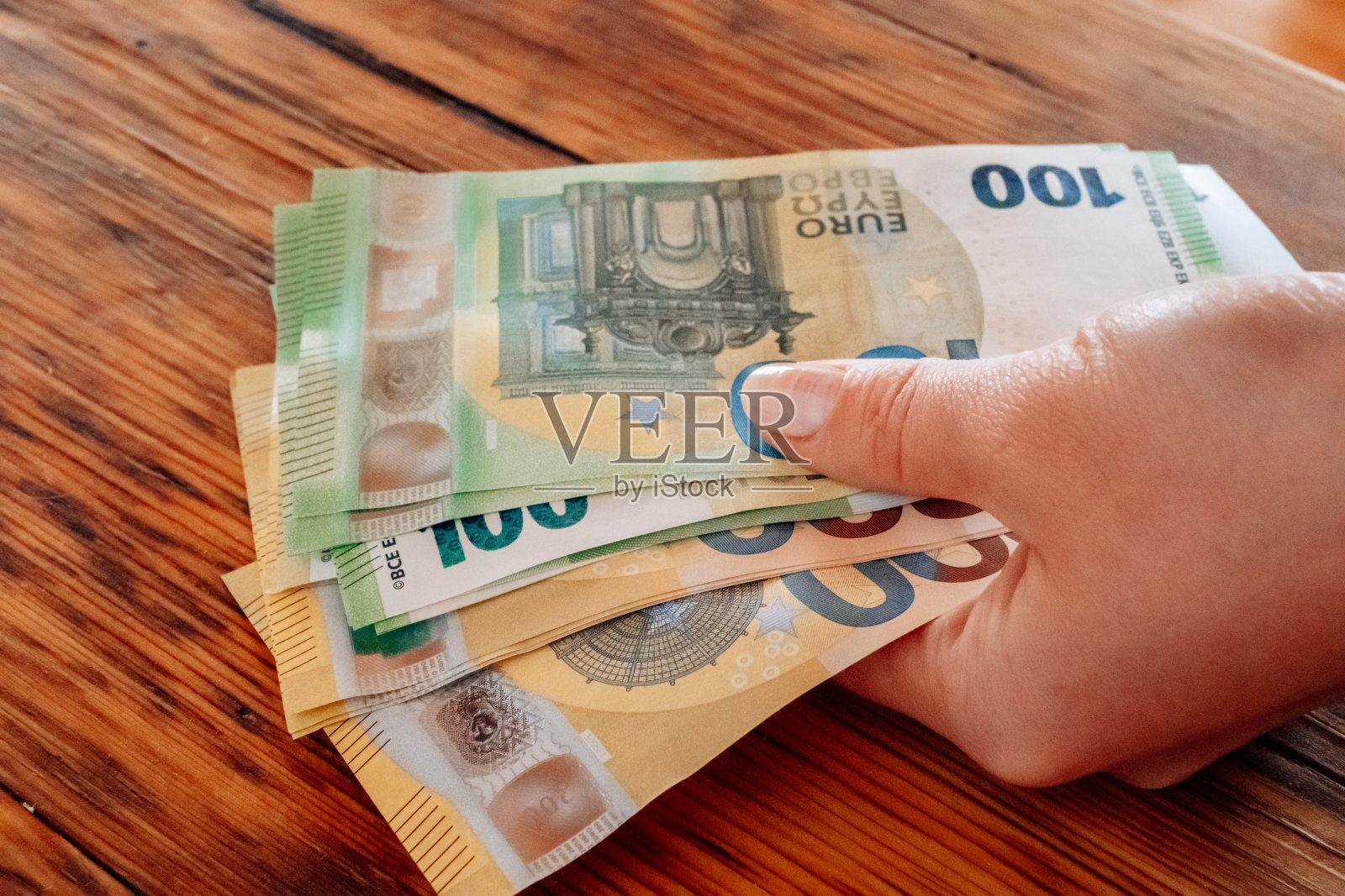 一百欧元钞票。桌上的手在数欧元。欧洲国家妇女的收入。欧盟的钱。欧元区的收入和支出。照片摄影图片