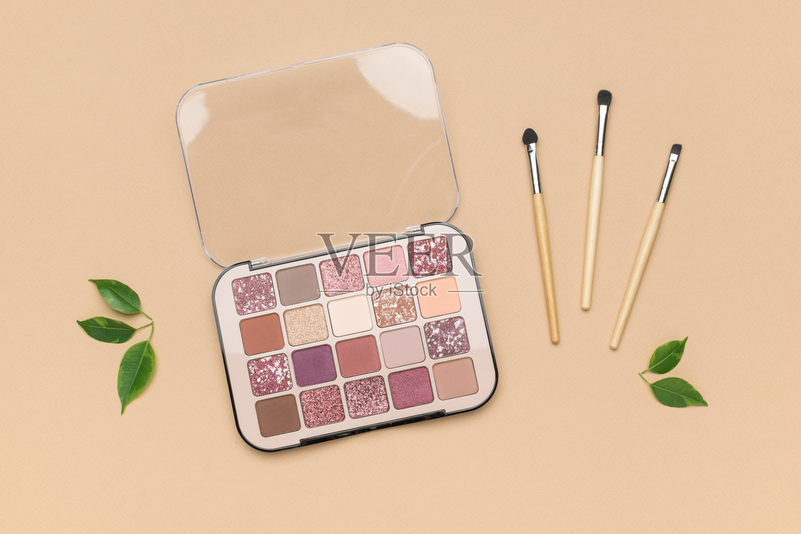 三个刷子和一套眼影在米色的背景。照片摄影图片