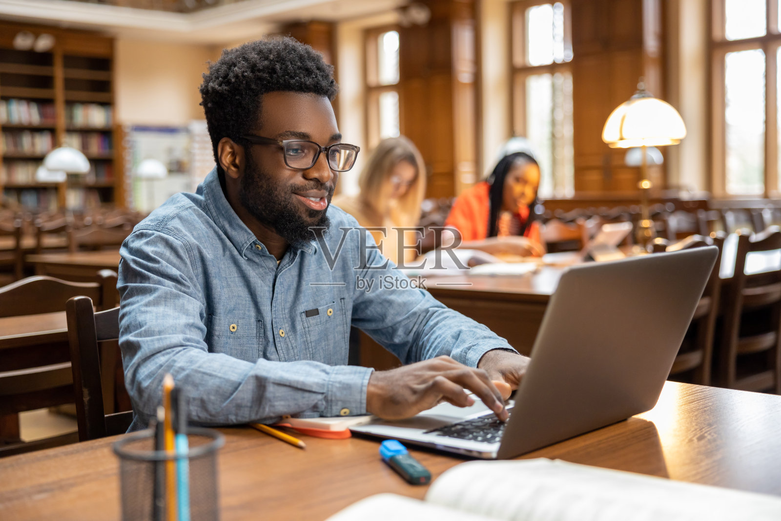 一个皮肤黝黑的年轻人在图书馆上网照片摄影图片