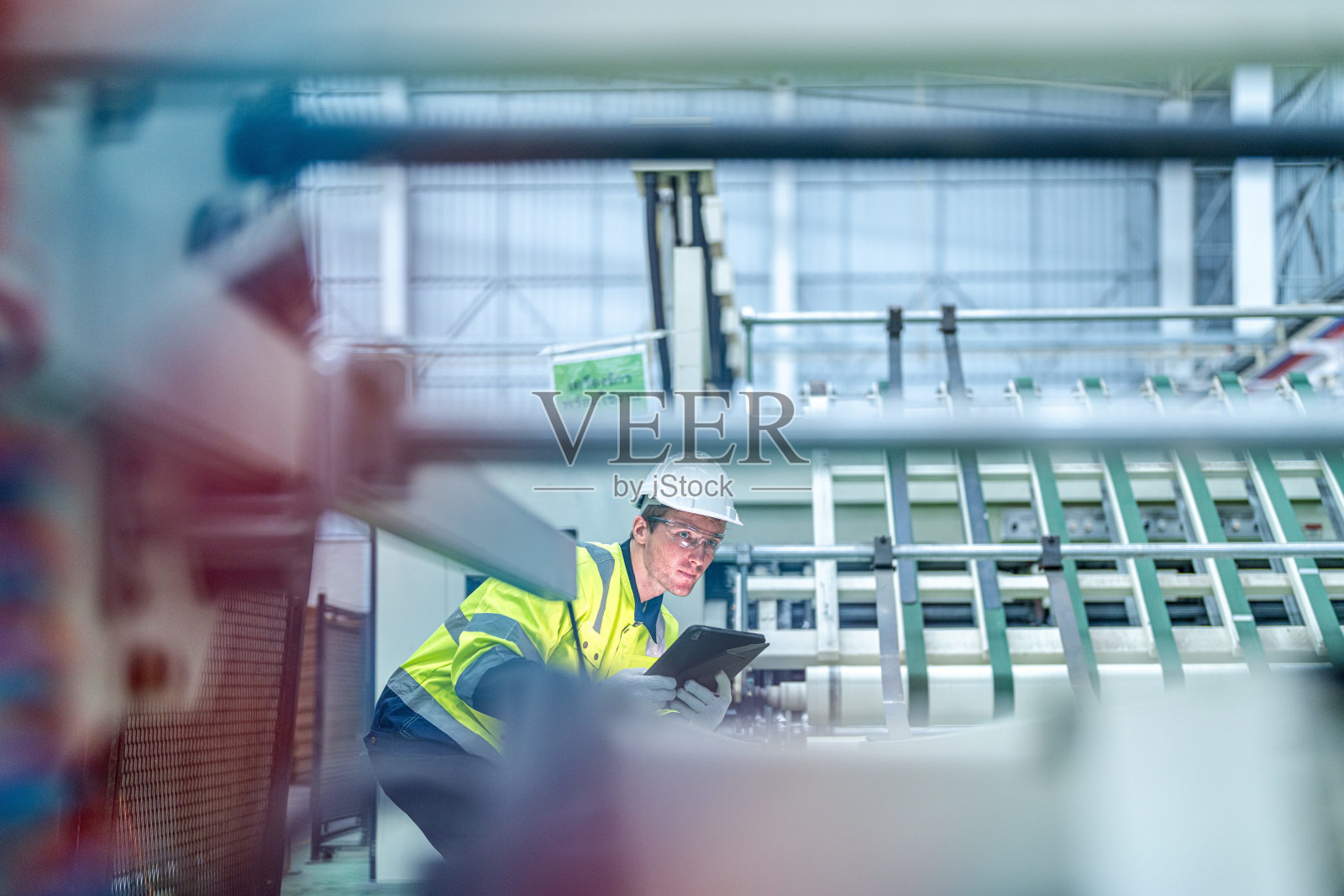 在一家生产工业技术产品的工厂里,穿着整洁工作服的男女工程师准备和控制大型现代机器的生产系统。照片摄影图片