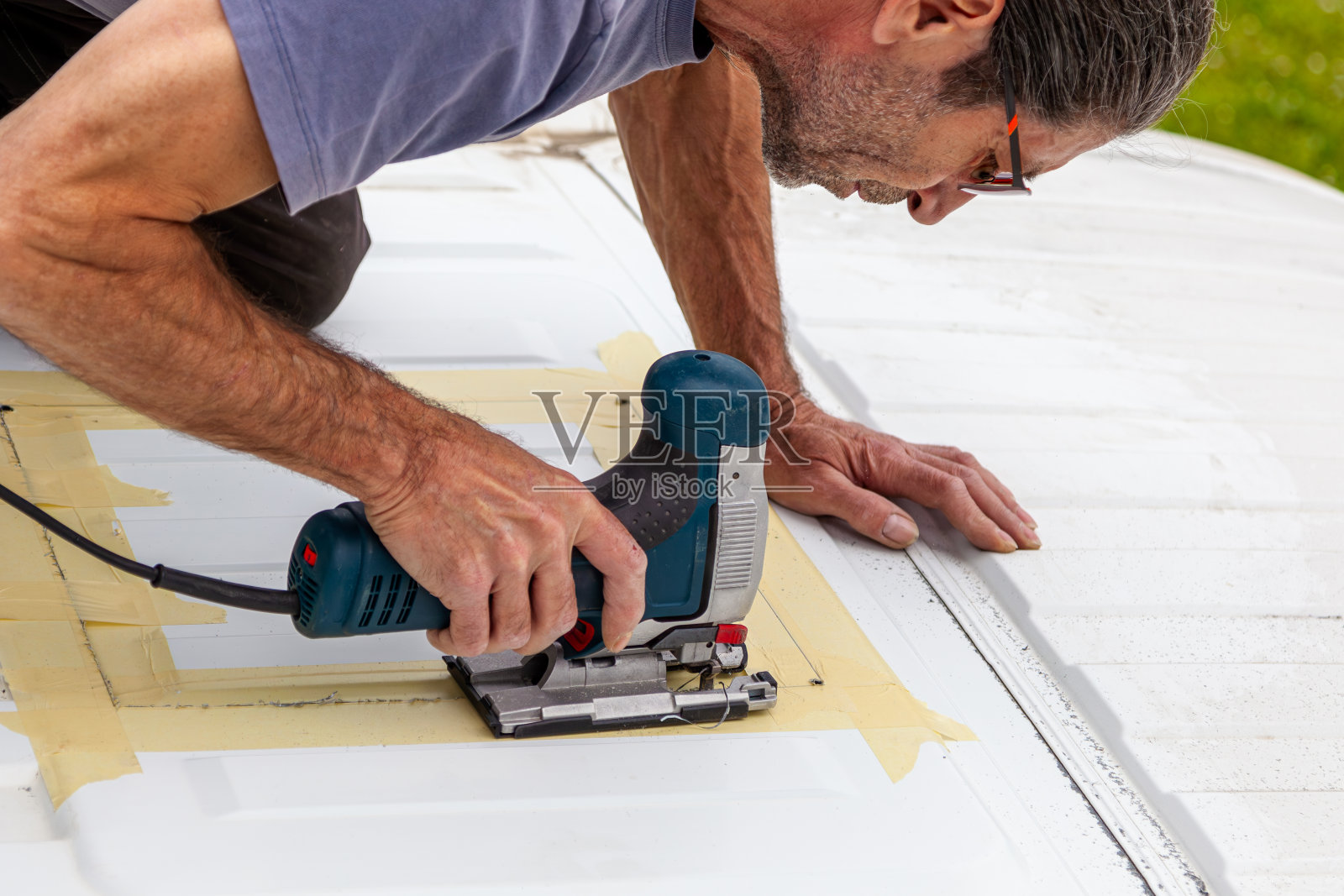 DIY露营车跳车转换。外面有个新窗户。用电动拼图机切割。安装顶窗前的准备工作。照片摄影图片