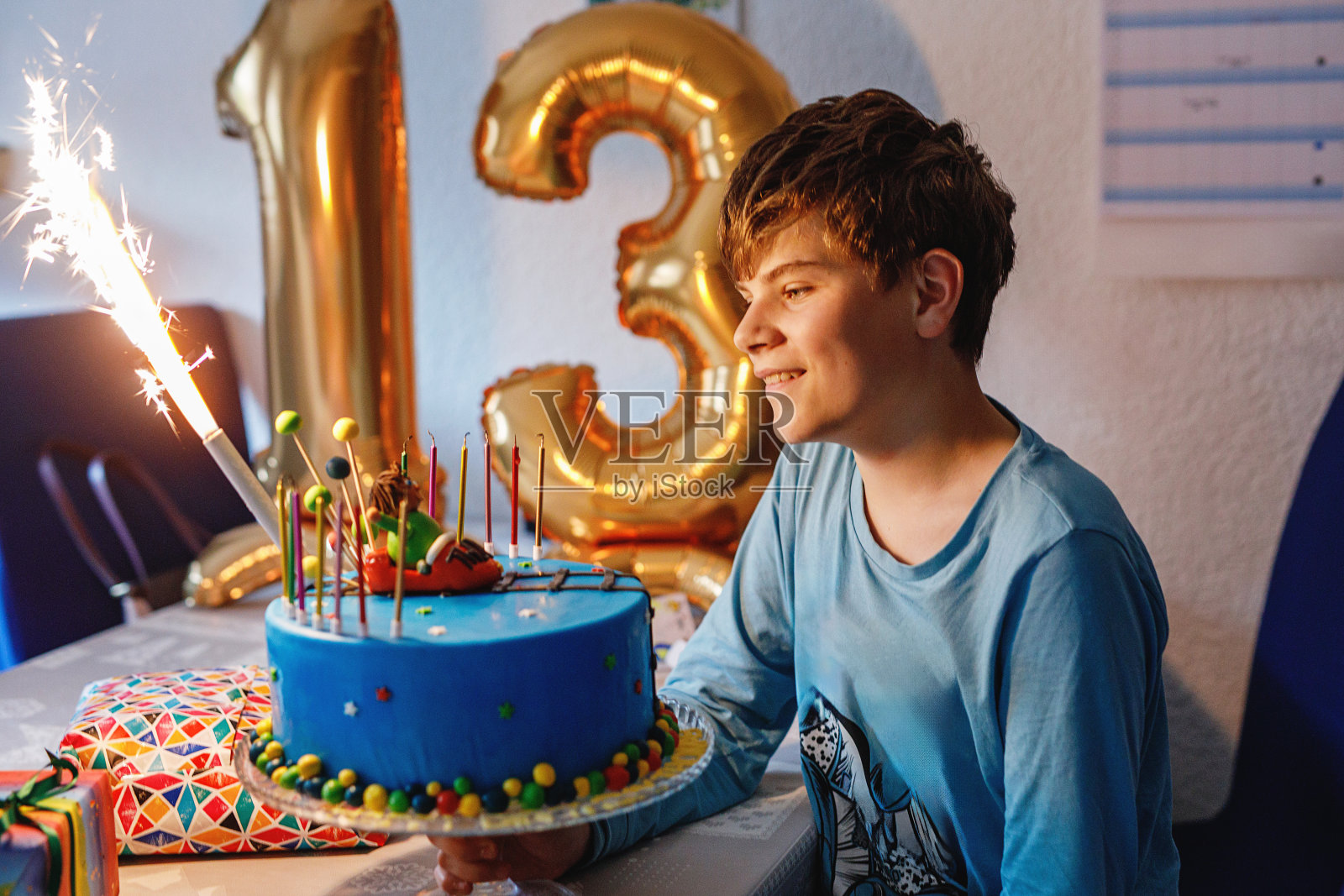 可爱快乐的金发小男孩庆祝他的生日。青春期前的孩子在室内自制的烤蛋糕上吹蜡烛。学生生日聚会,家庭庆祝活动,青少年生日照片摄影图片