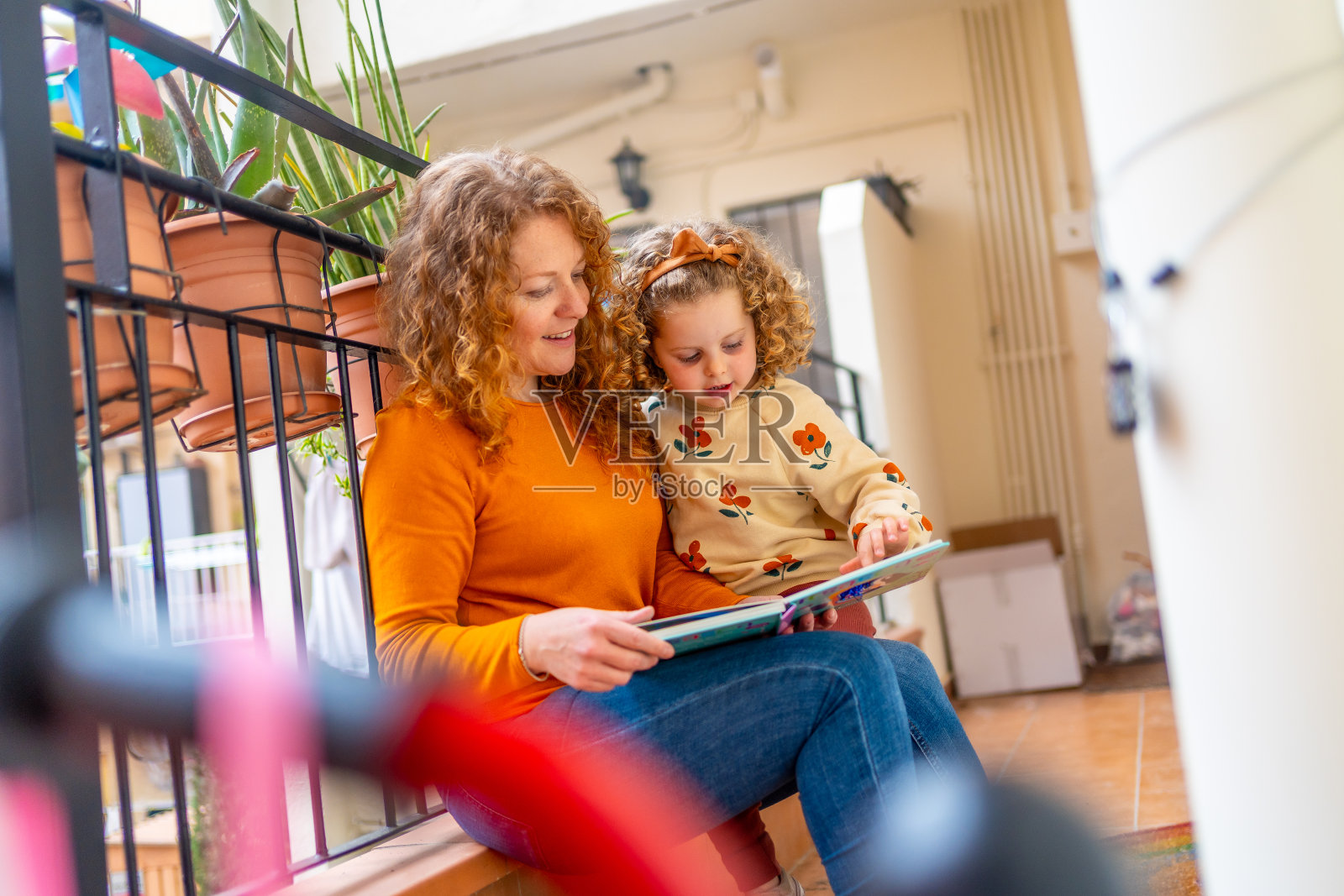 一个女人和一个女孩在阳台上看书照片摄影图片
