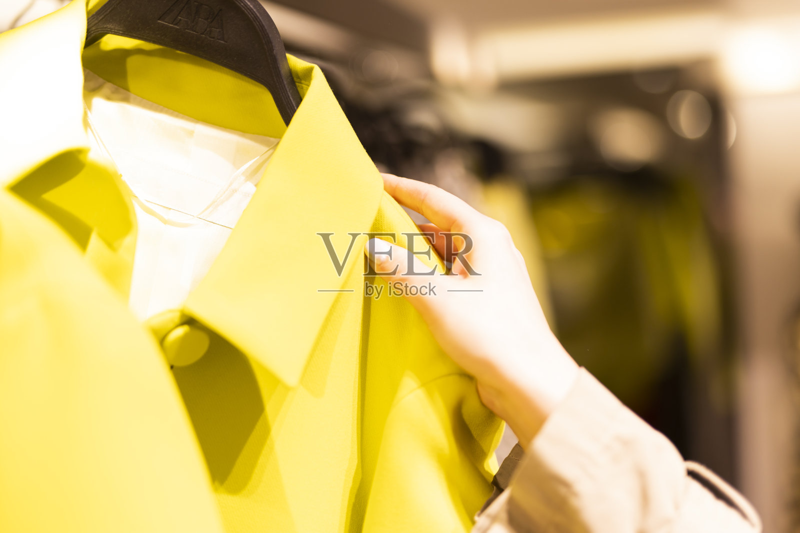 在服装店挑选一件明黄色的夹克照片摄影图片