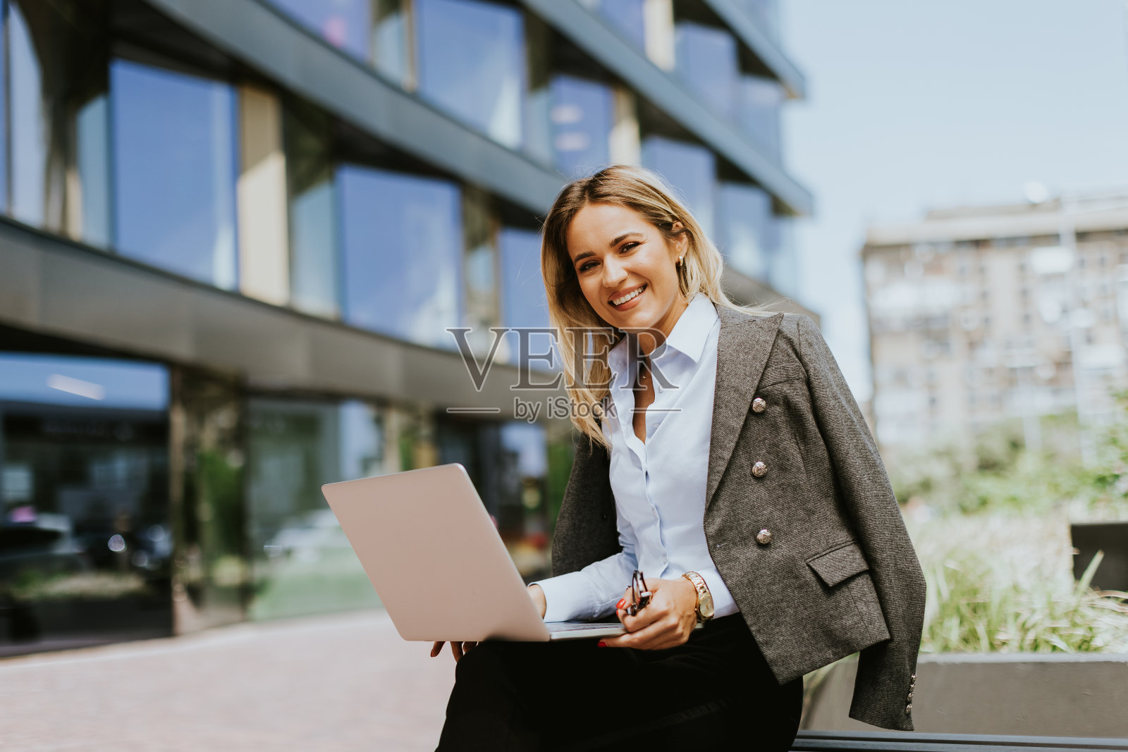 白天在现代办公楼外用笔记本电脑工作的职业女商人照片摄影图片