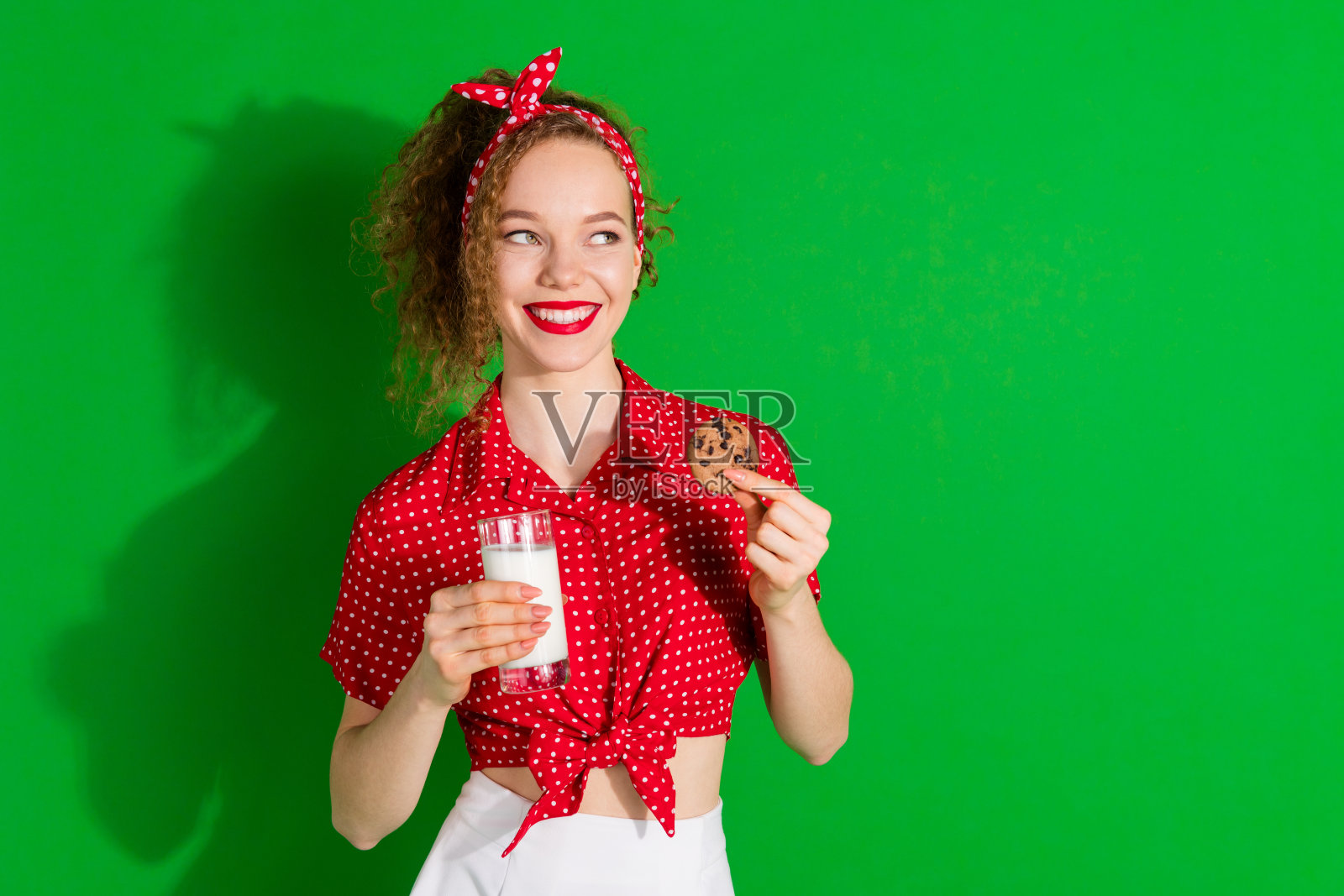 照片肖像可爱的年轻女士看起来空的空间牛奶玻璃饼干穿着时尚的红色复古服装孤立在绿色的背景照片摄影图片