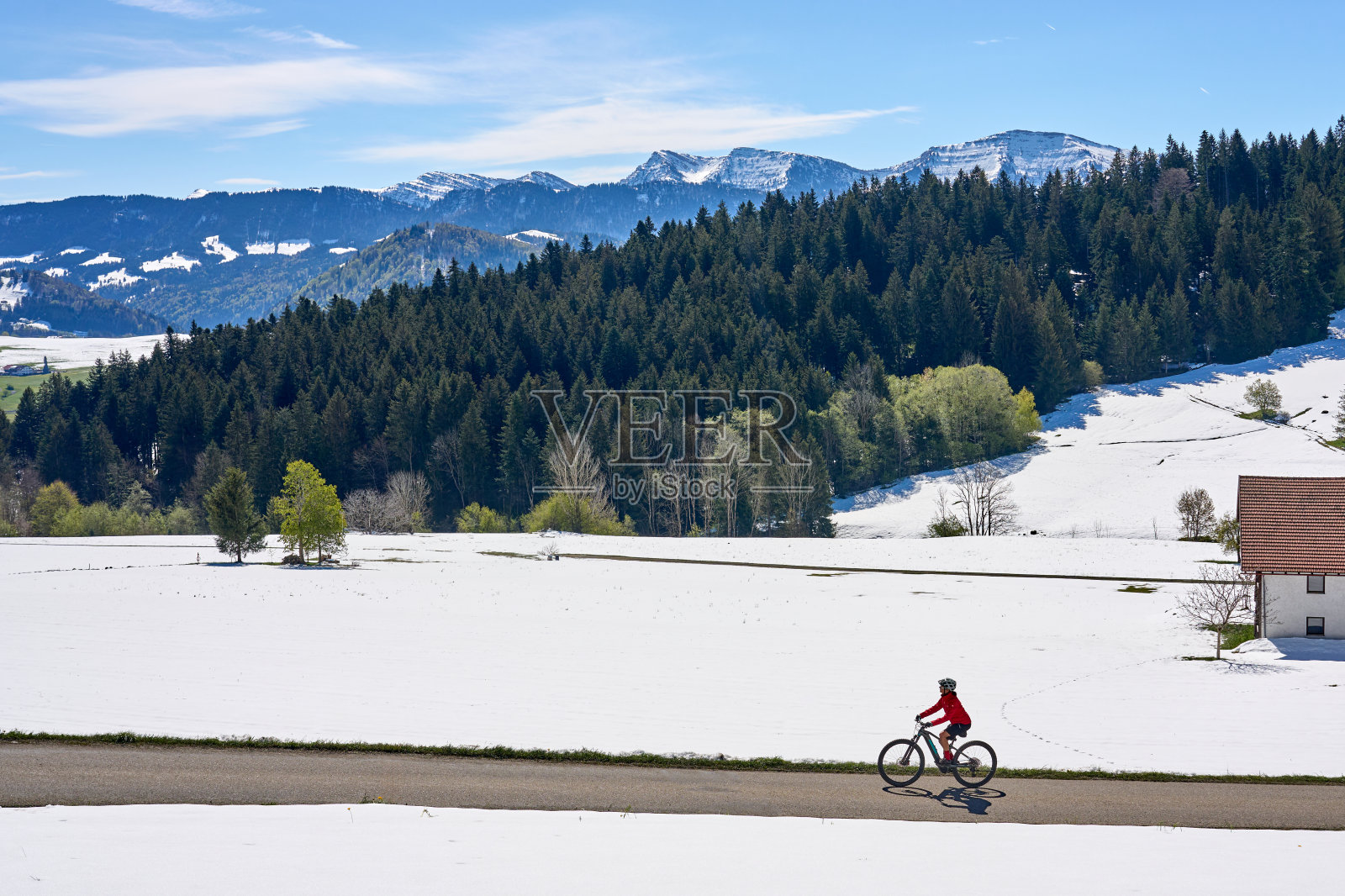 女子在雪山和草地之间骑行照片摄影图片