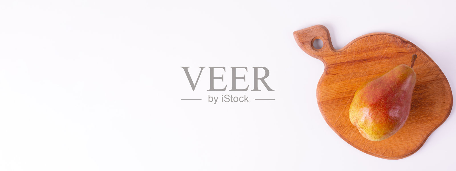 一个红色的梨放在一个木制砧板上,背景是白色的照片摄影图片