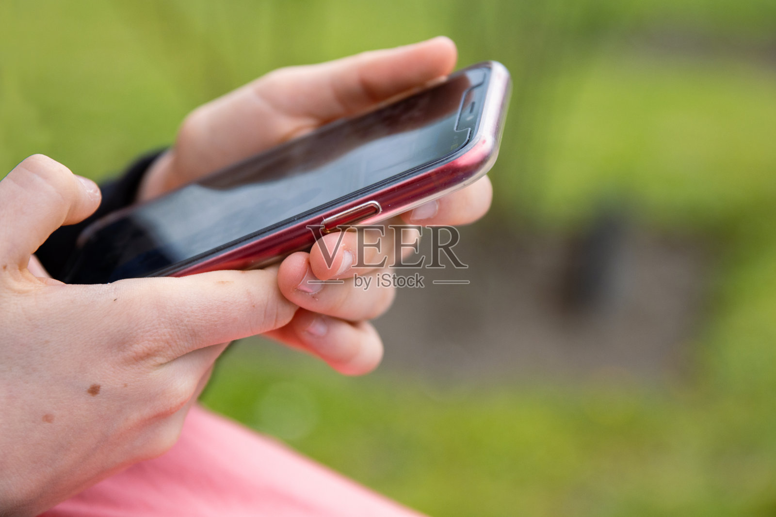 拇指手指在红色手机的黑屏上。人发短信,潮人触摸智能手机屏幕。女孩的手拿着滚动工作。夏天的公园。关闭了。副本的空间。有选择性的重点照片摄影图片