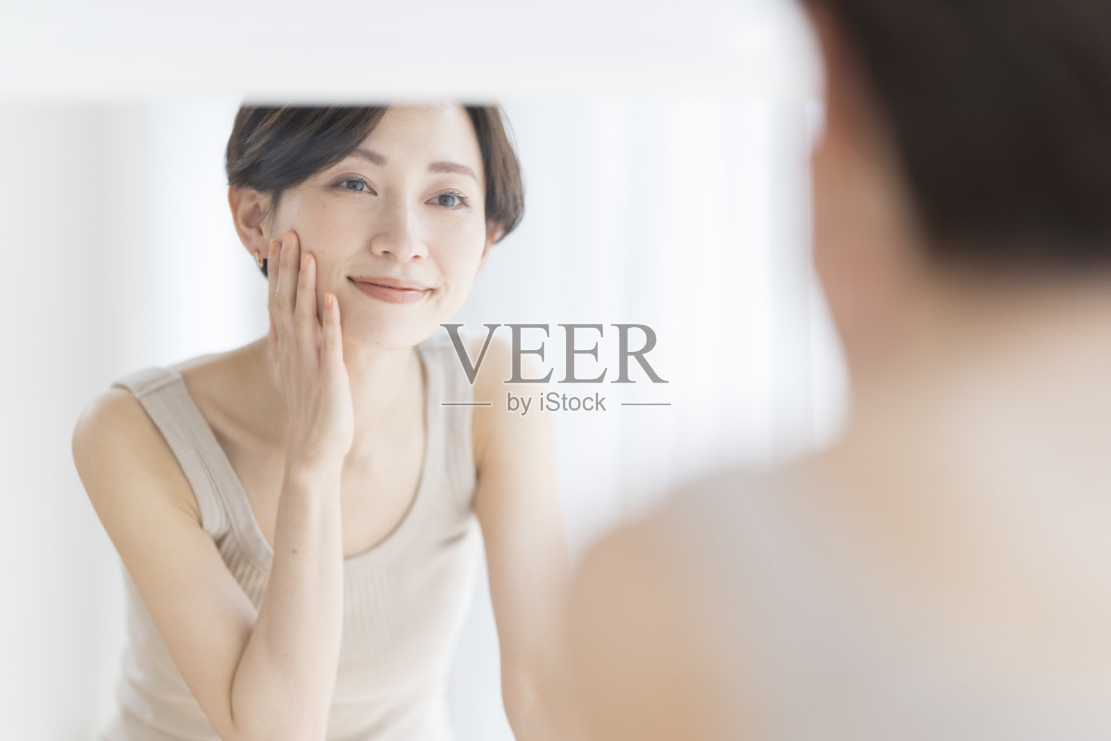 皮肤护理。一个女人照镜子时摸着自己的脸。照片摄影图片