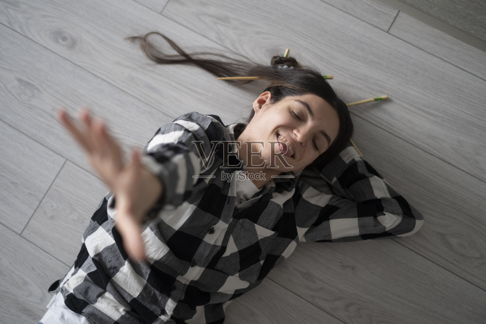 穿着格子衬衫的快乐女孩躺在家里的木地板上享受这一刻照片摄影图片