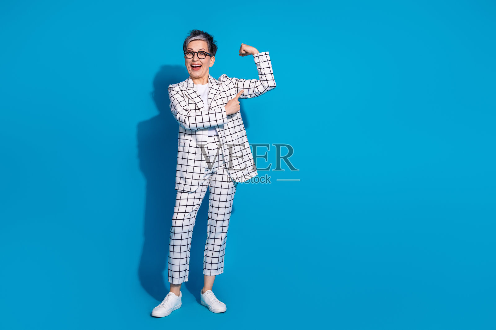 照片中美丽开朗的女人穿着白色时尚的衣服,肌肉空白的空间孤立在蓝色的背景上照片摄影图片