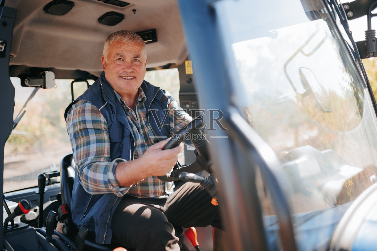 控制老年农民在农业环境下操作拖拉机照片摄影图片