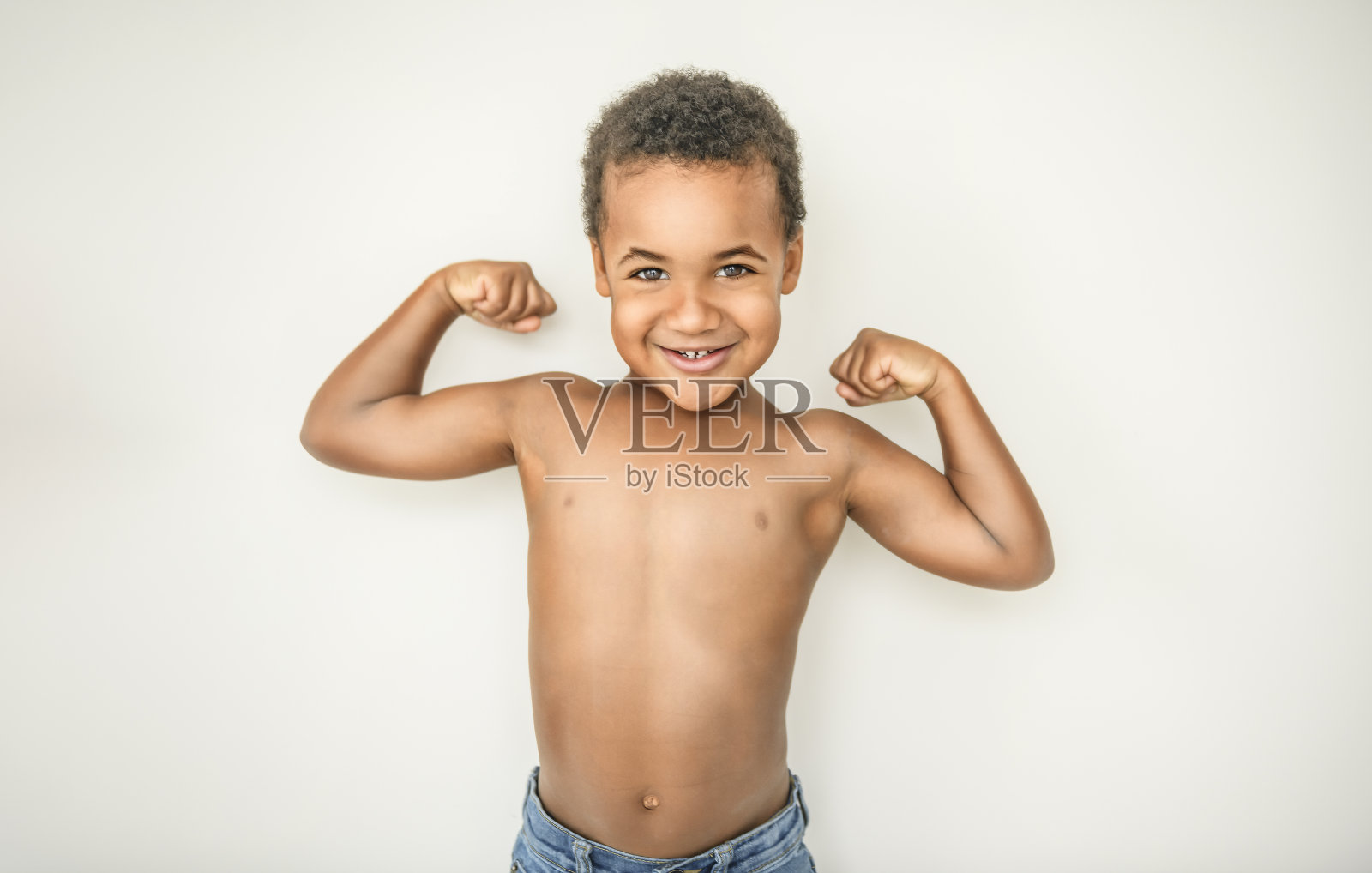 可爱快乐的3岁美国男孩对着镜头微笑,展示他的肌肉照片摄影图片