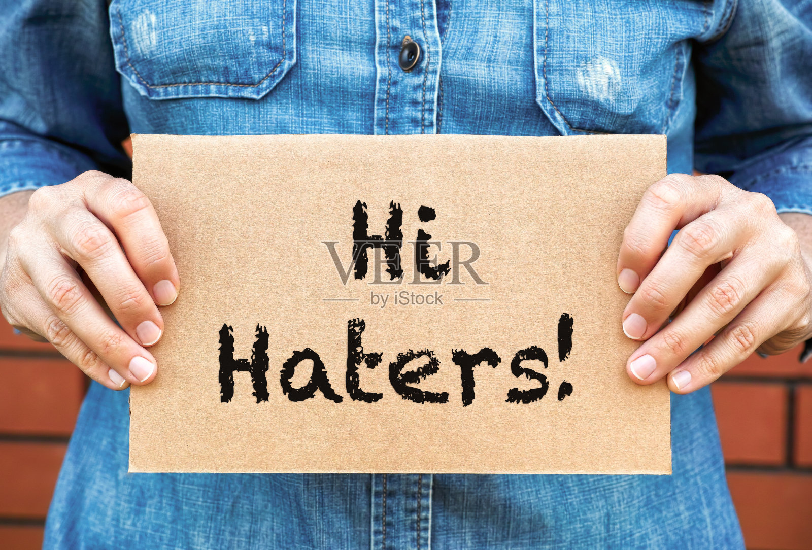 一名女子拿着一块纸板,上面写着“嗨,仇恨者”照片摄影图片