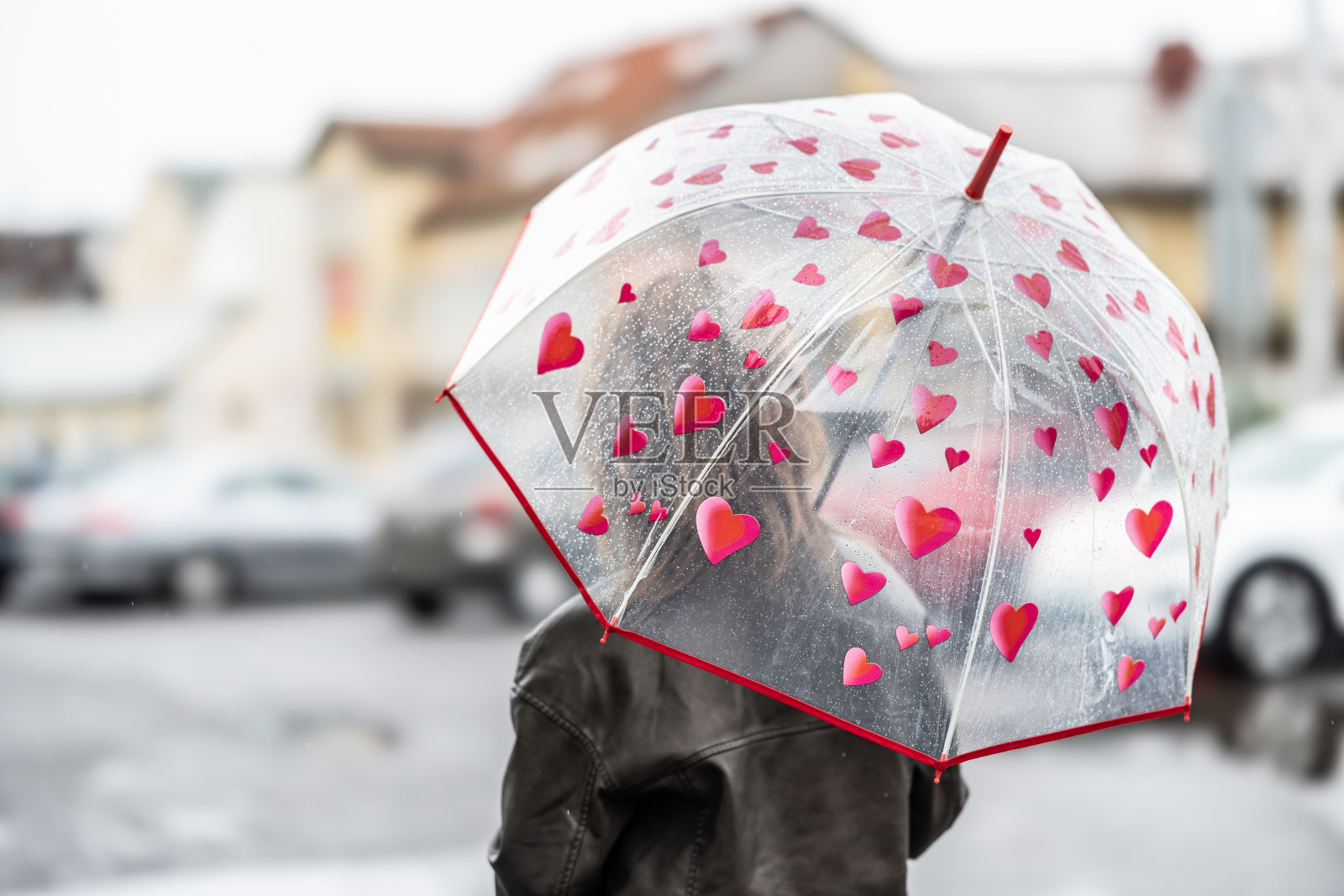一个女人在下雨天撑伞的后视图。照片摄影图片