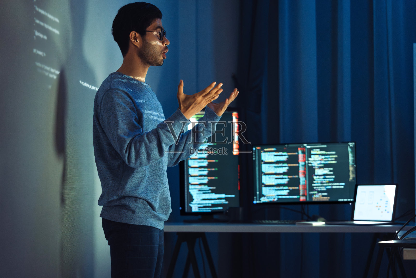 印度男子程序员站在屏幕前,用代码投影演示软件开发中技术和人类专业知识的集成照片摄影图片