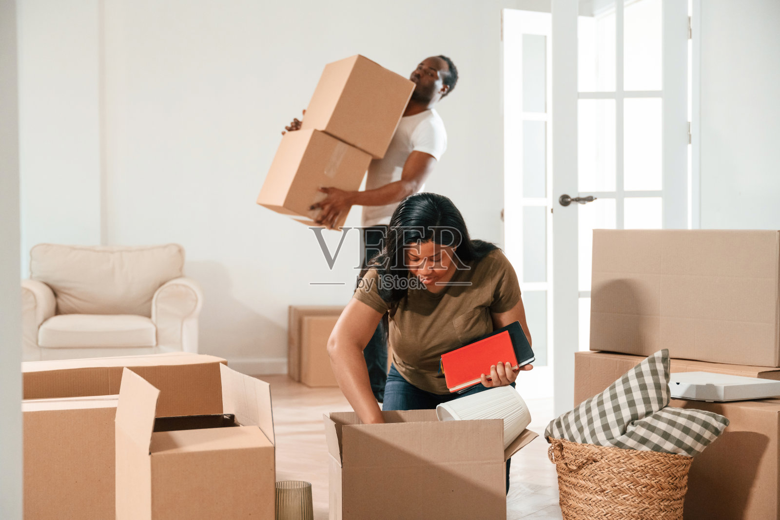 那家伙拿着很多箱子。一对非裔美国夫妇要搬进新家了照片摄影图片