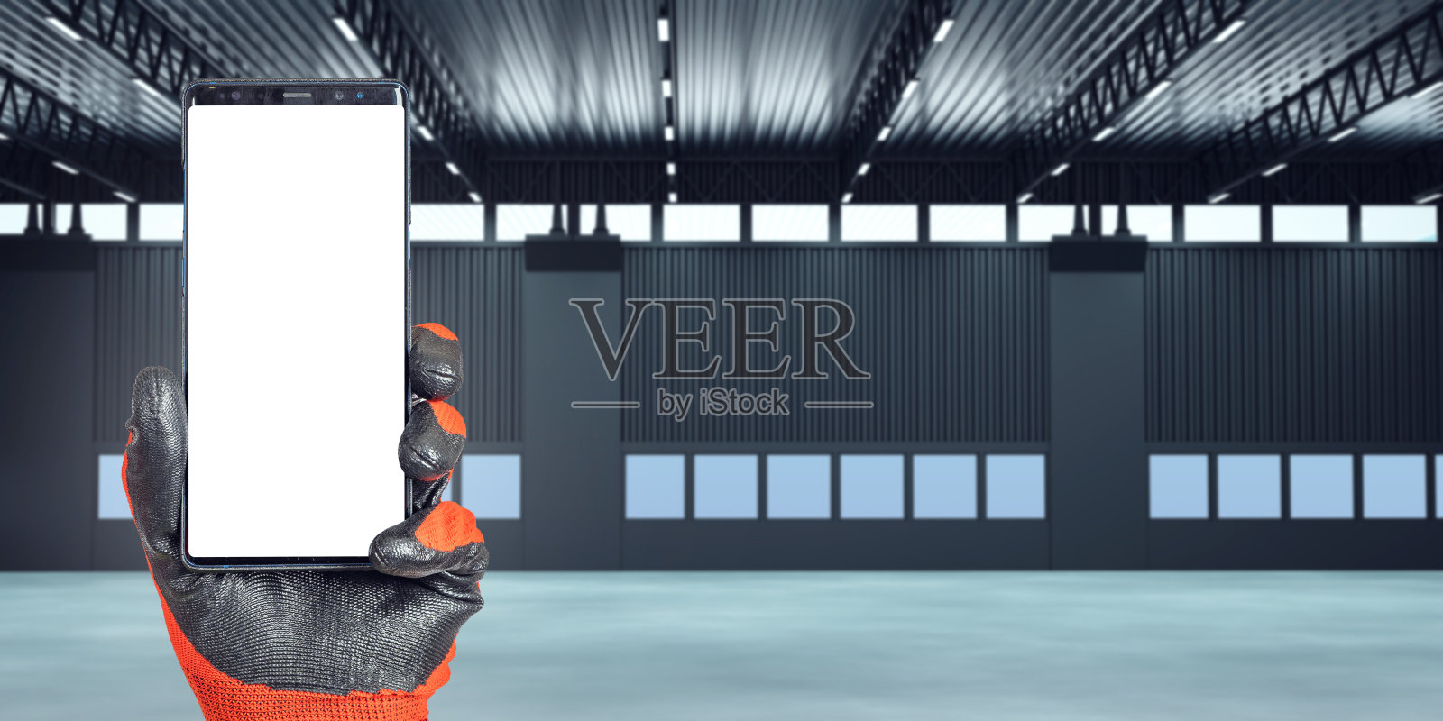 手机在手。空置大楼内的智能手机模板。仓库租赁建筑的概念。白屏手机。租用仓库空间。仓库公司所在地。艺术的焦点。照片摄影图片