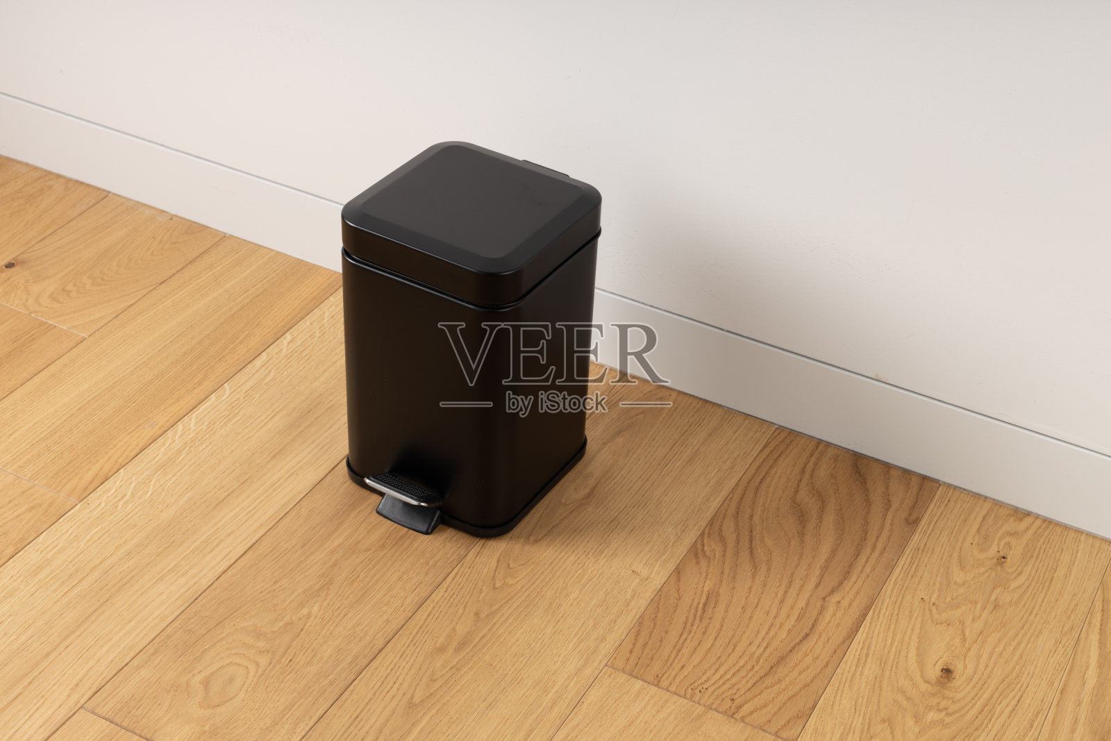 木质地板上的黑色脚踏垃圾桶照片摄影图片
