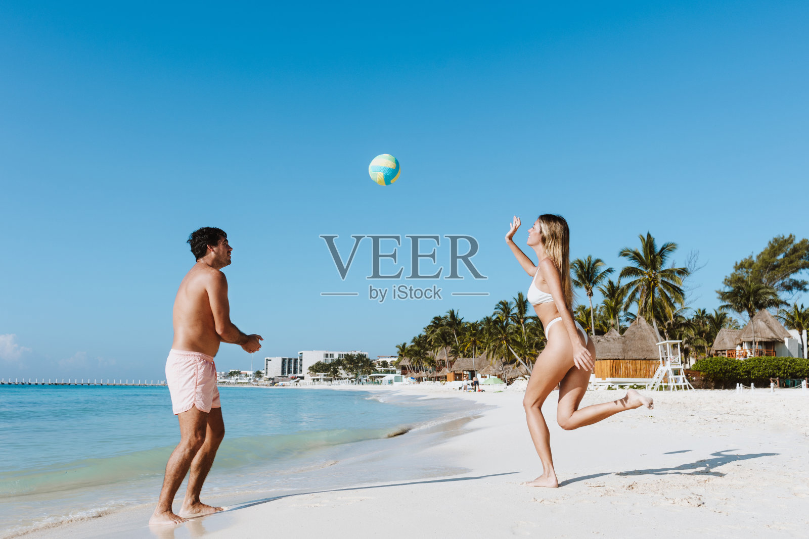 在拉丁美洲墨西哥的加勒比海墨西哥海滩上,西班牙裔年轻夫妇一起打排球,玩得很开心照片摄影图片