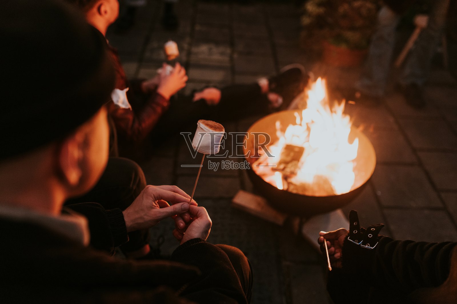 朋友们一起在篝火旁吃棉花糖和棉花糖照片摄影图片