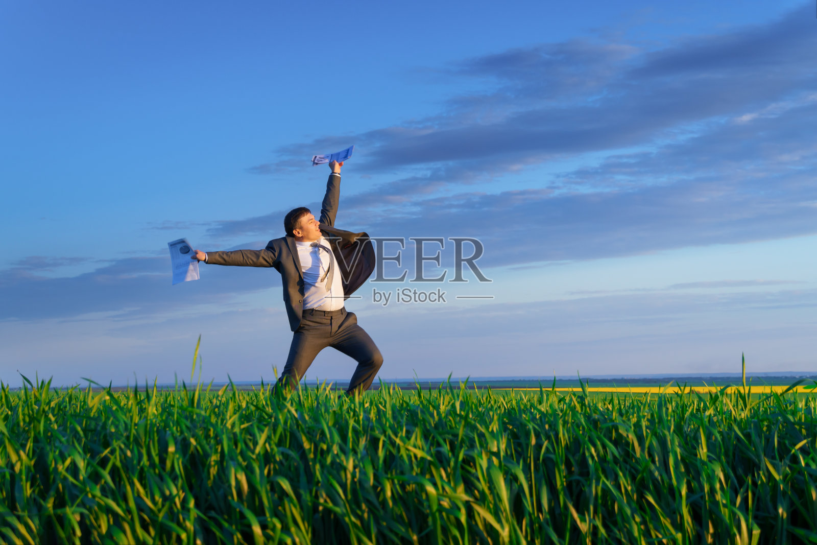 一个商人愉快地跳上一片绿草地,休闲或自由职业的概念照片摄影图片