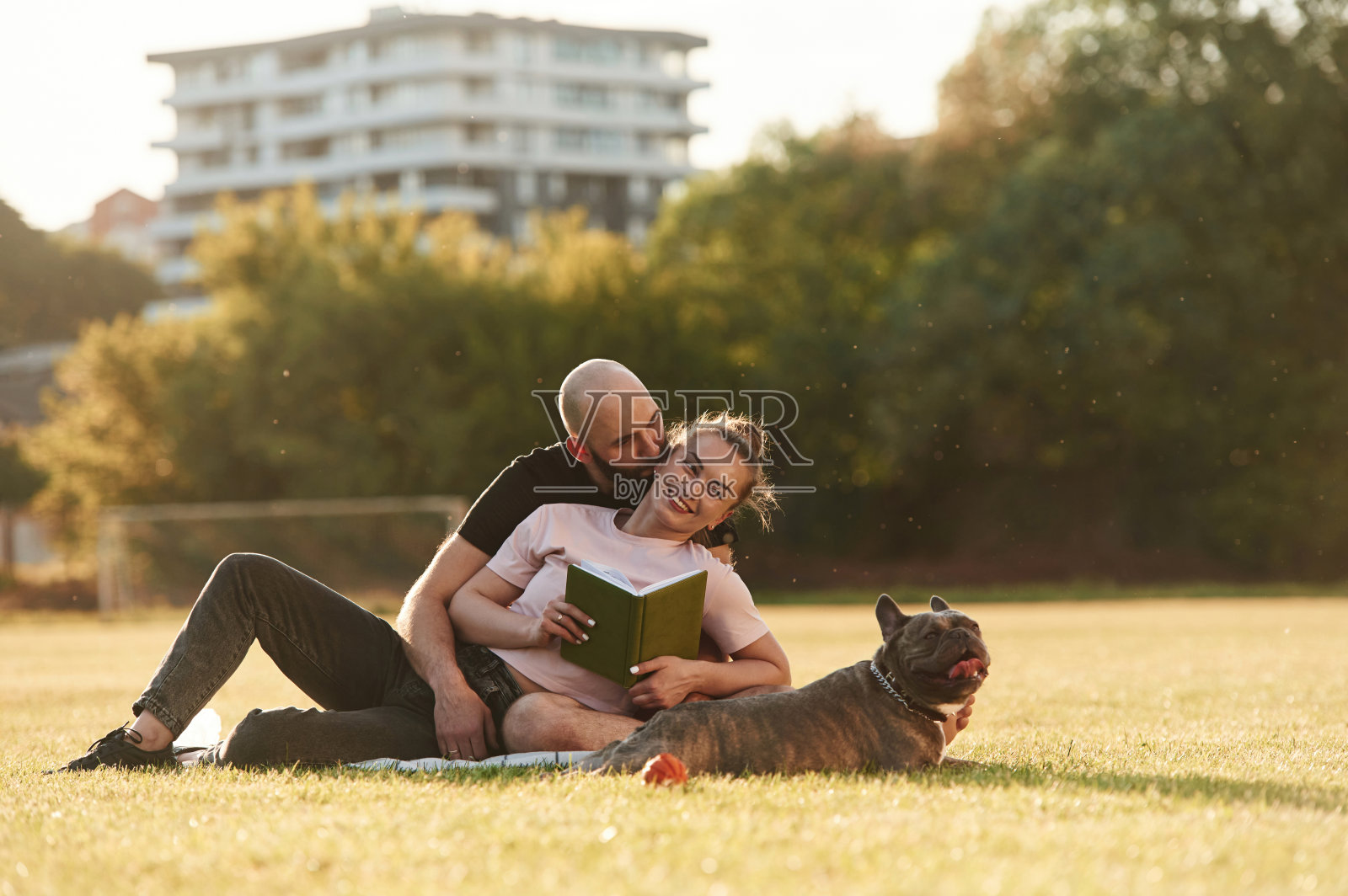 周末时间,休息和坐着。一男一女带着狗在操场上照片摄影图片