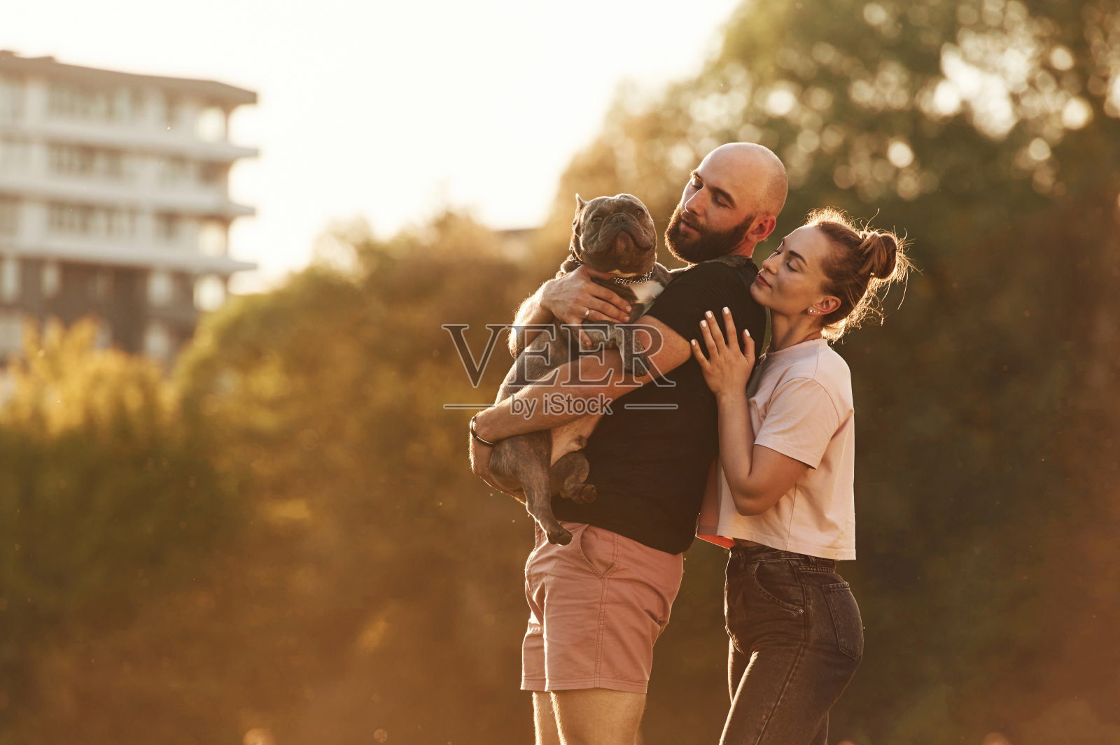 可爱的夫妇,手里抱着小动物。一男一女带着狗在操场上照片摄影图片