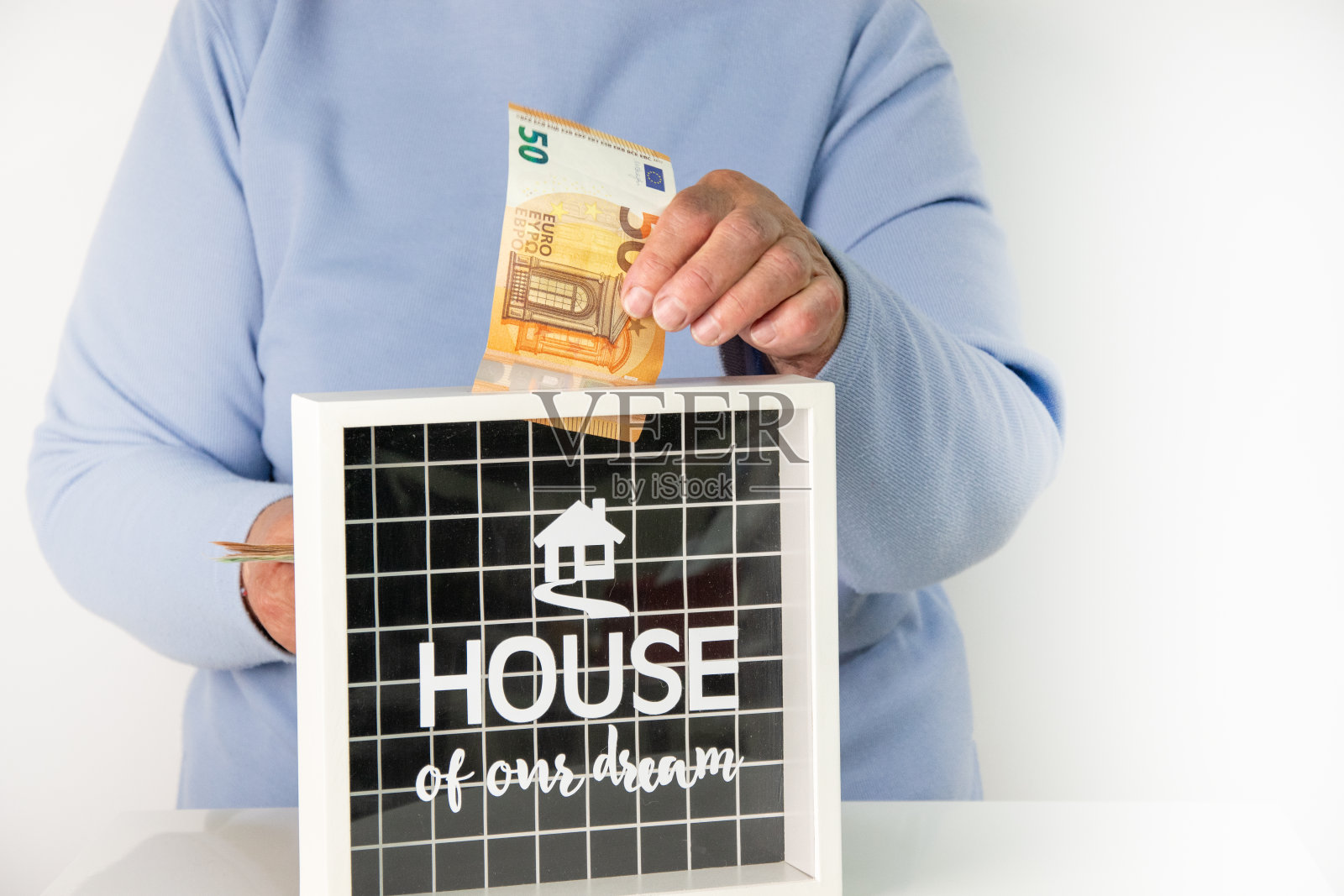 一个人把一张50欧元的钞票放进一个标有“我们的梦想之家”的盒子里照片摄影图片