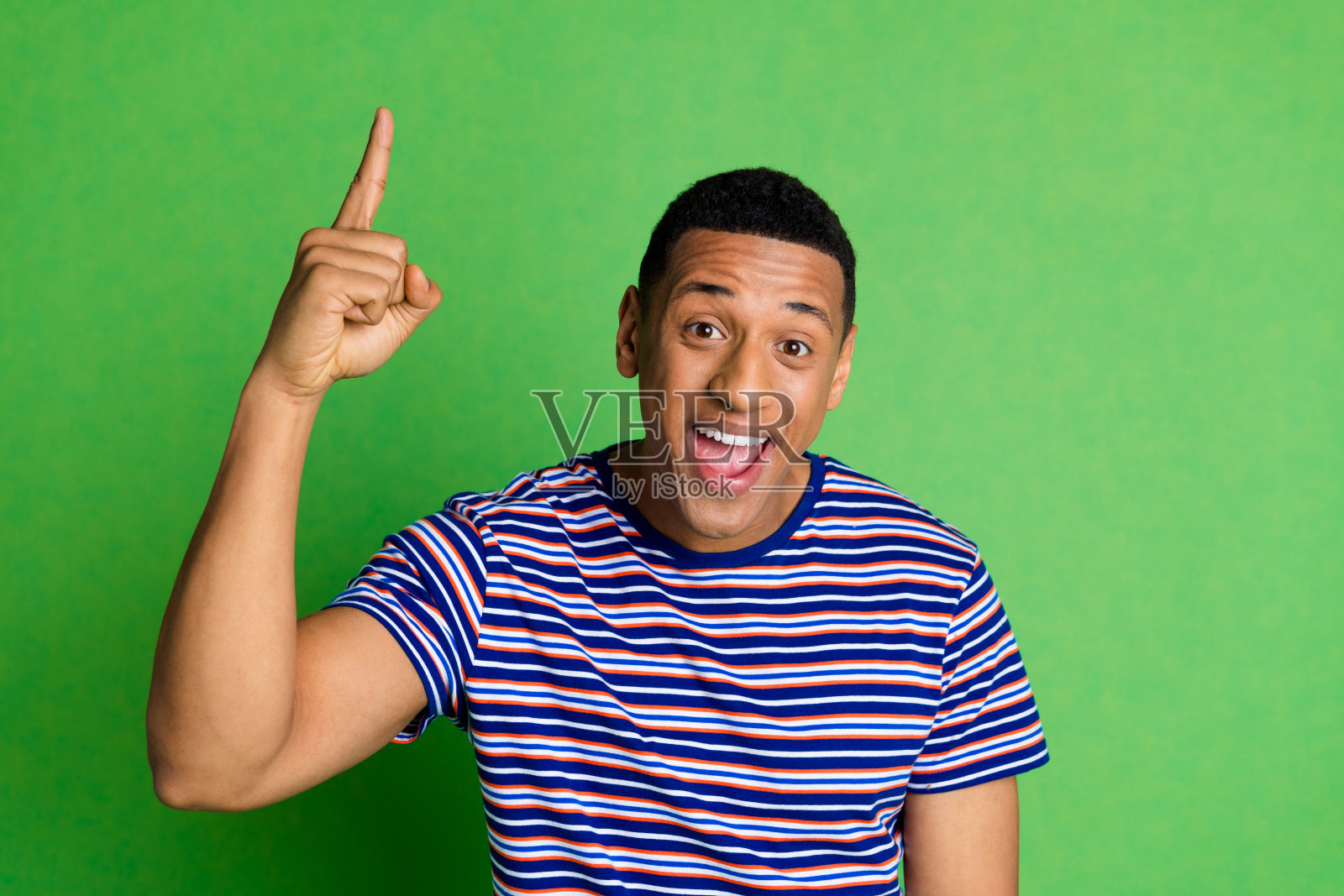 漂亮的年轻人的肖像,用手指指着穿在绿色背景上的t恤照片摄影图片