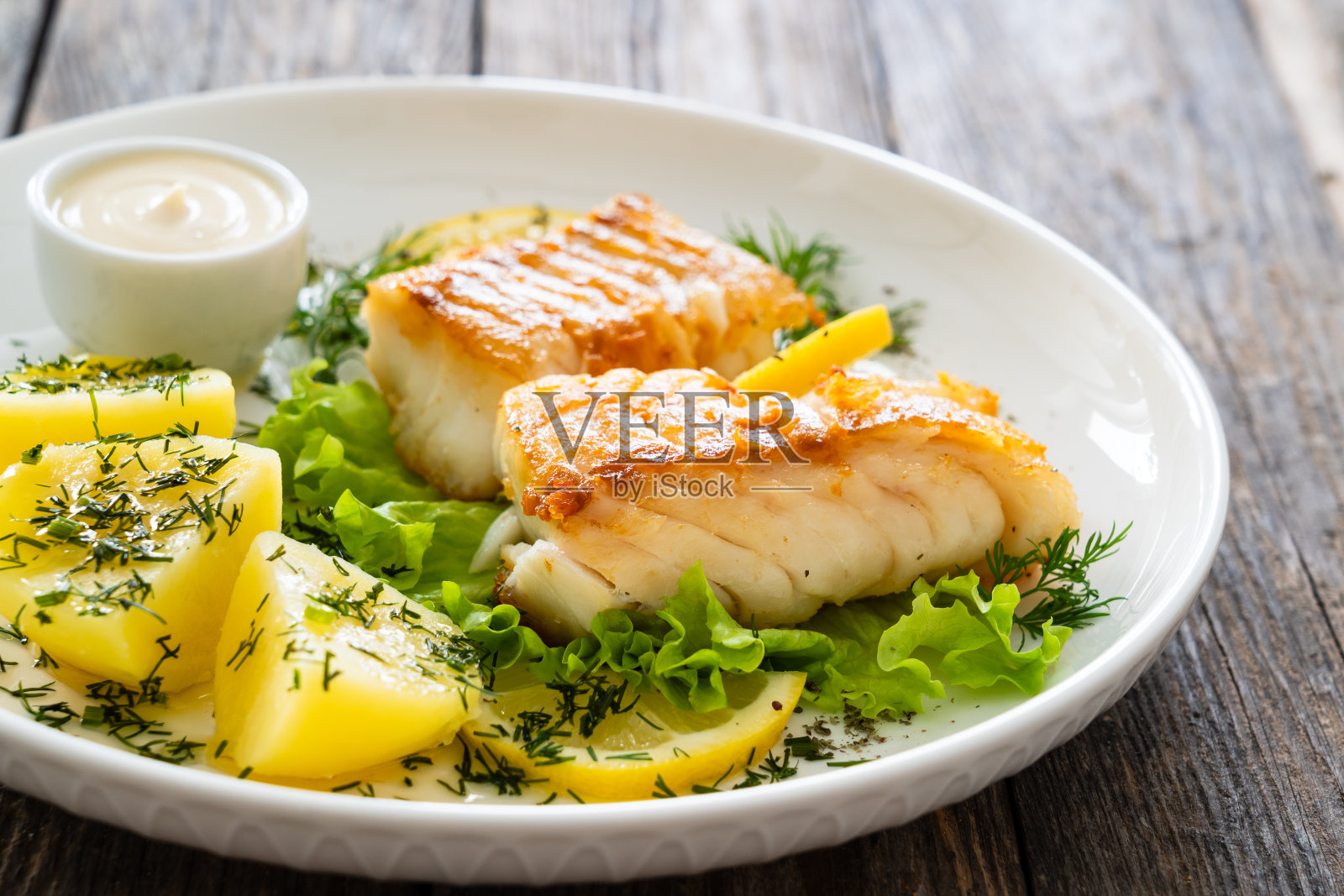 木桌上的煎鳕鱼片和煮土豆照片摄影图片