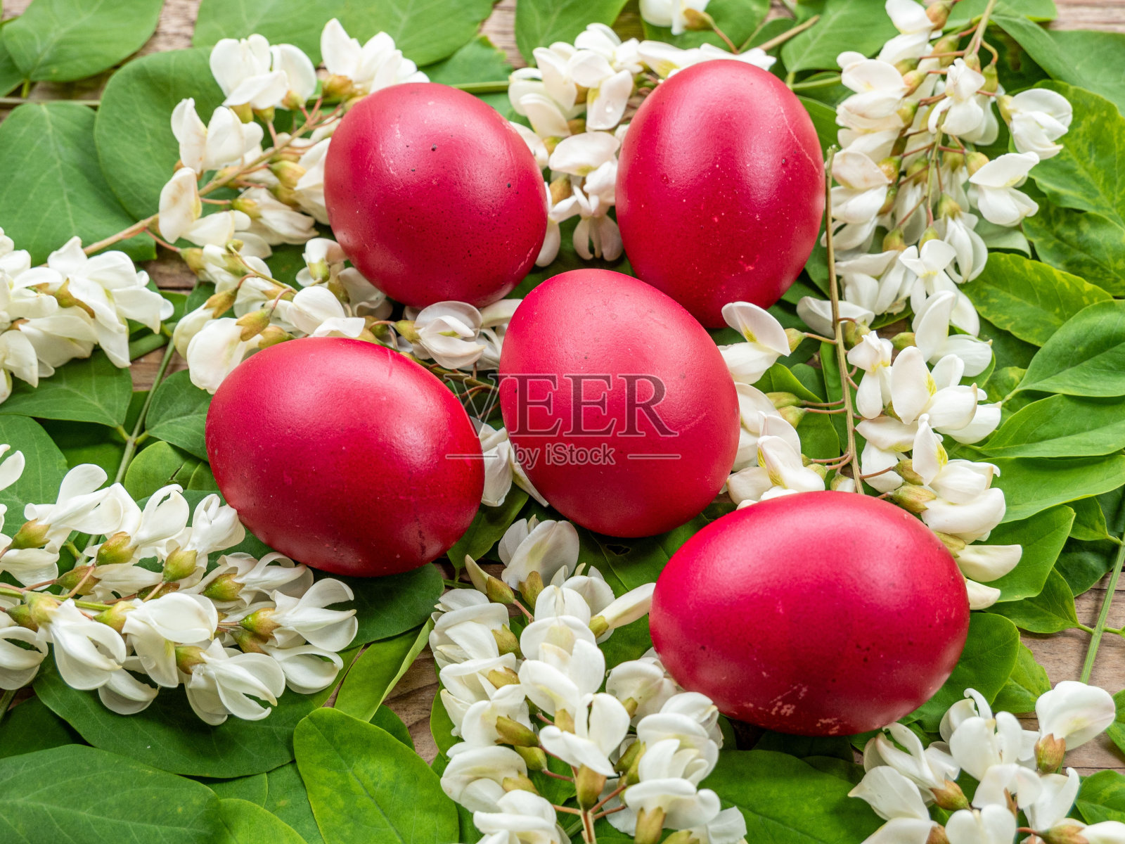 红色的复活节彩蛋,上面有白色的花朵和绿色的叶子。照片摄影图片