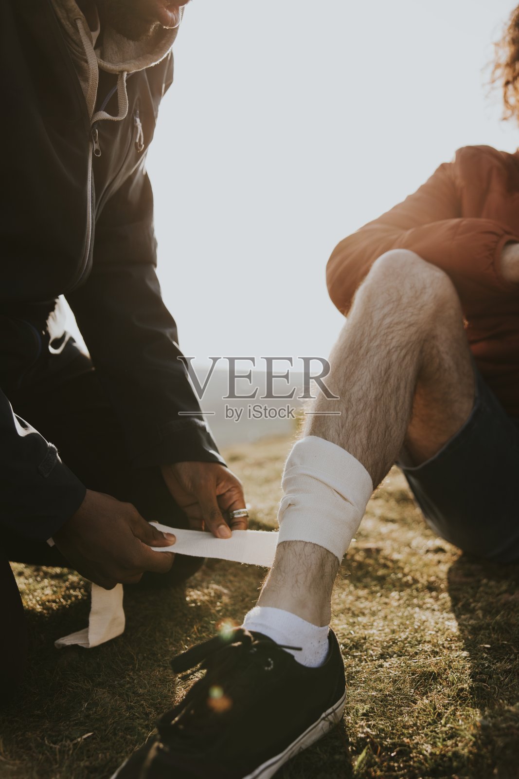 在朋友腿上缠绷带的人照片摄影图片