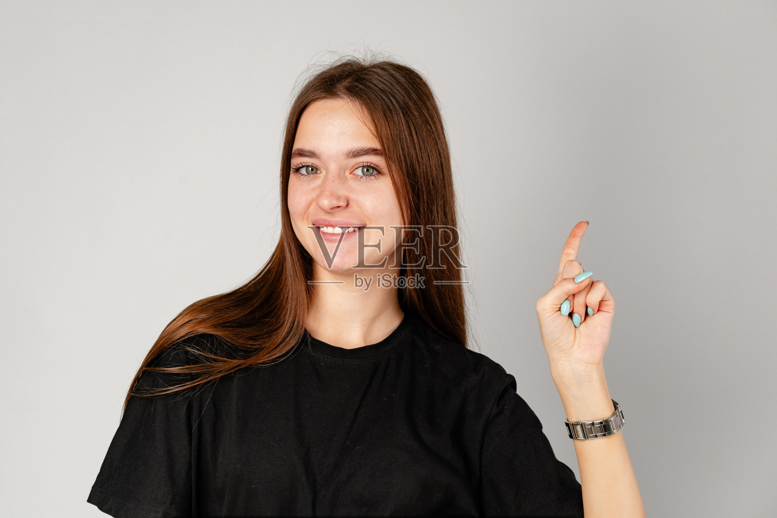 微笑的年轻女子指着灰色背景下的复制空间照片摄影图片