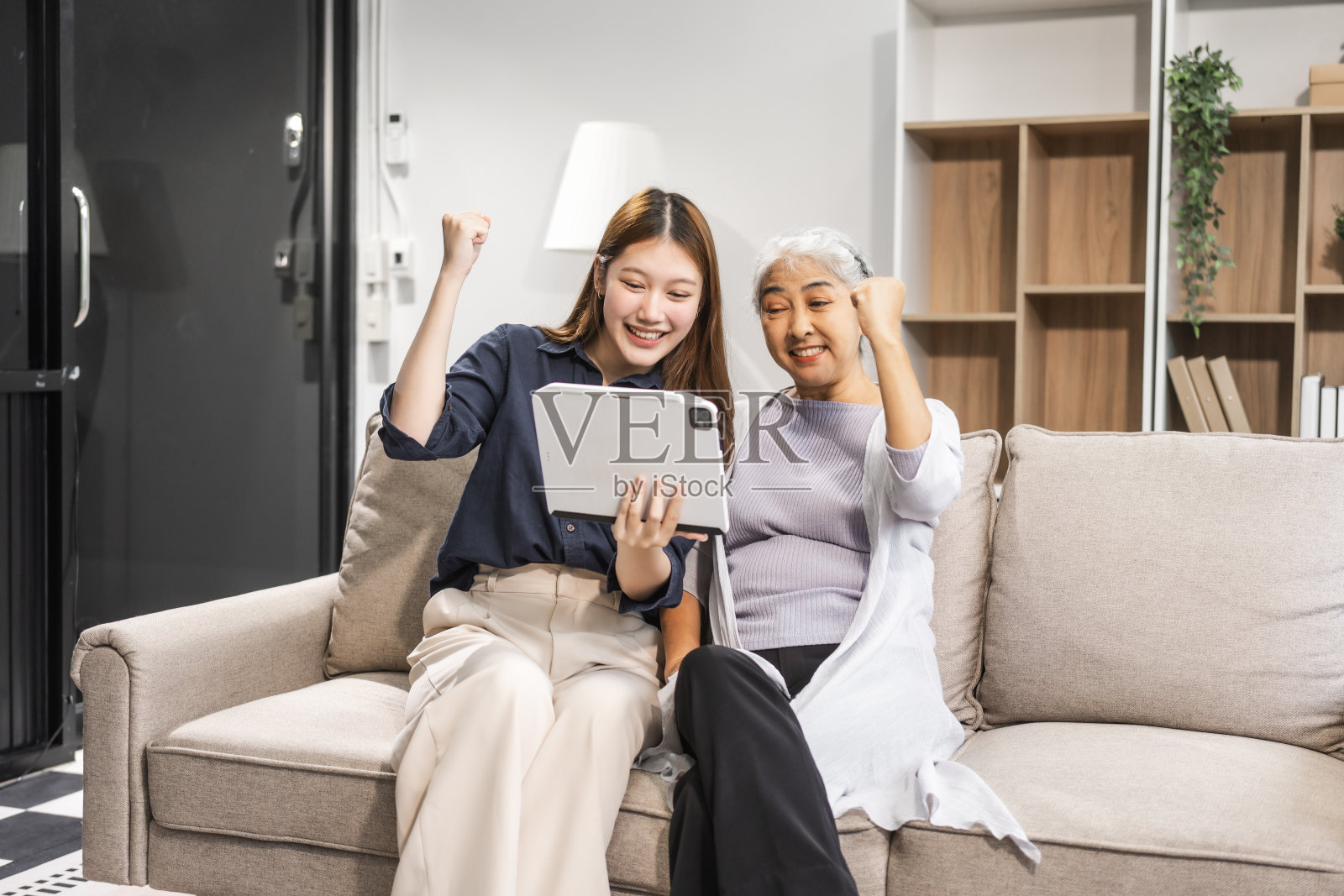 一位成熟的母亲和她年幼的女儿,都是亚洲人,坐在沙发上庆祝母亲节。他们分享舒适、亲密、温暖,用温柔、欢笑和珍贵的回忆拥抱他们的纽带。照片摄影图片