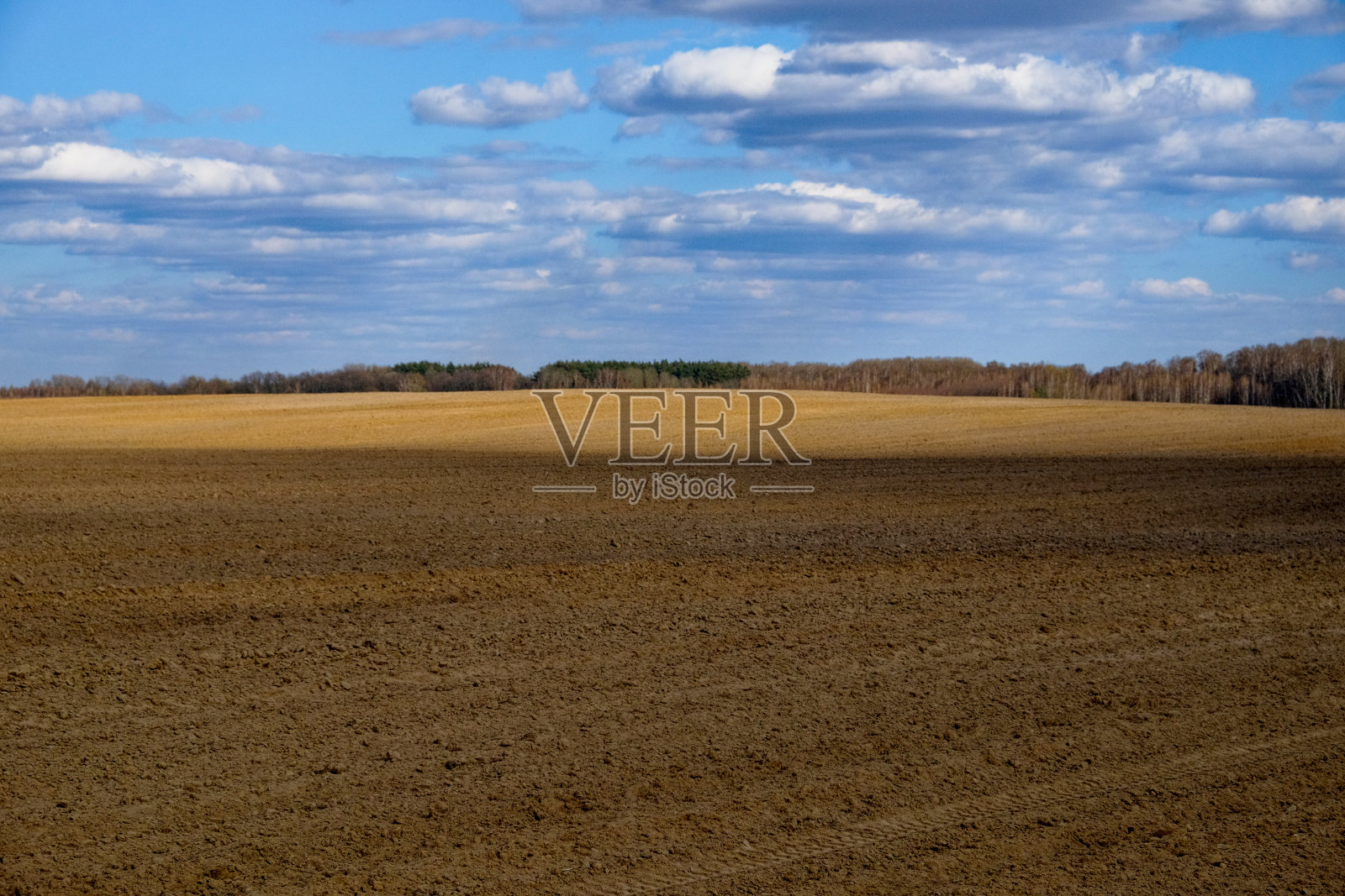 这张照片显示了多云天空下广阔的耕地。照片摄影图片