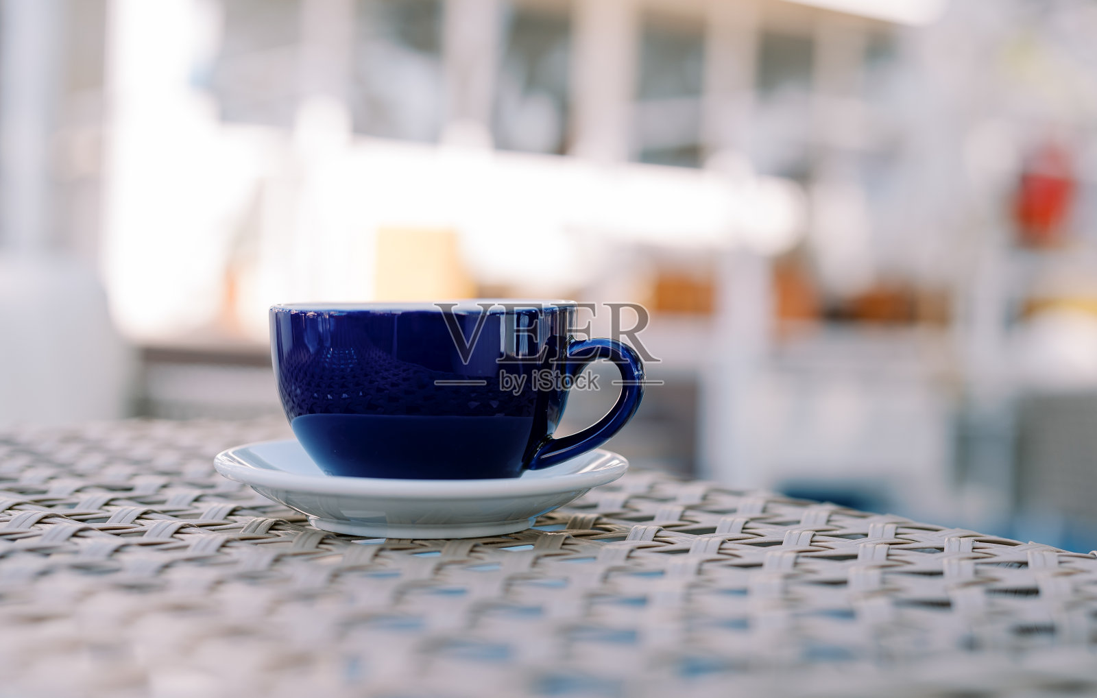 在一家户外咖啡馆里,柳条桌子上放着一杯拿铁,碟子上放着一杯拿铁照片摄影图片