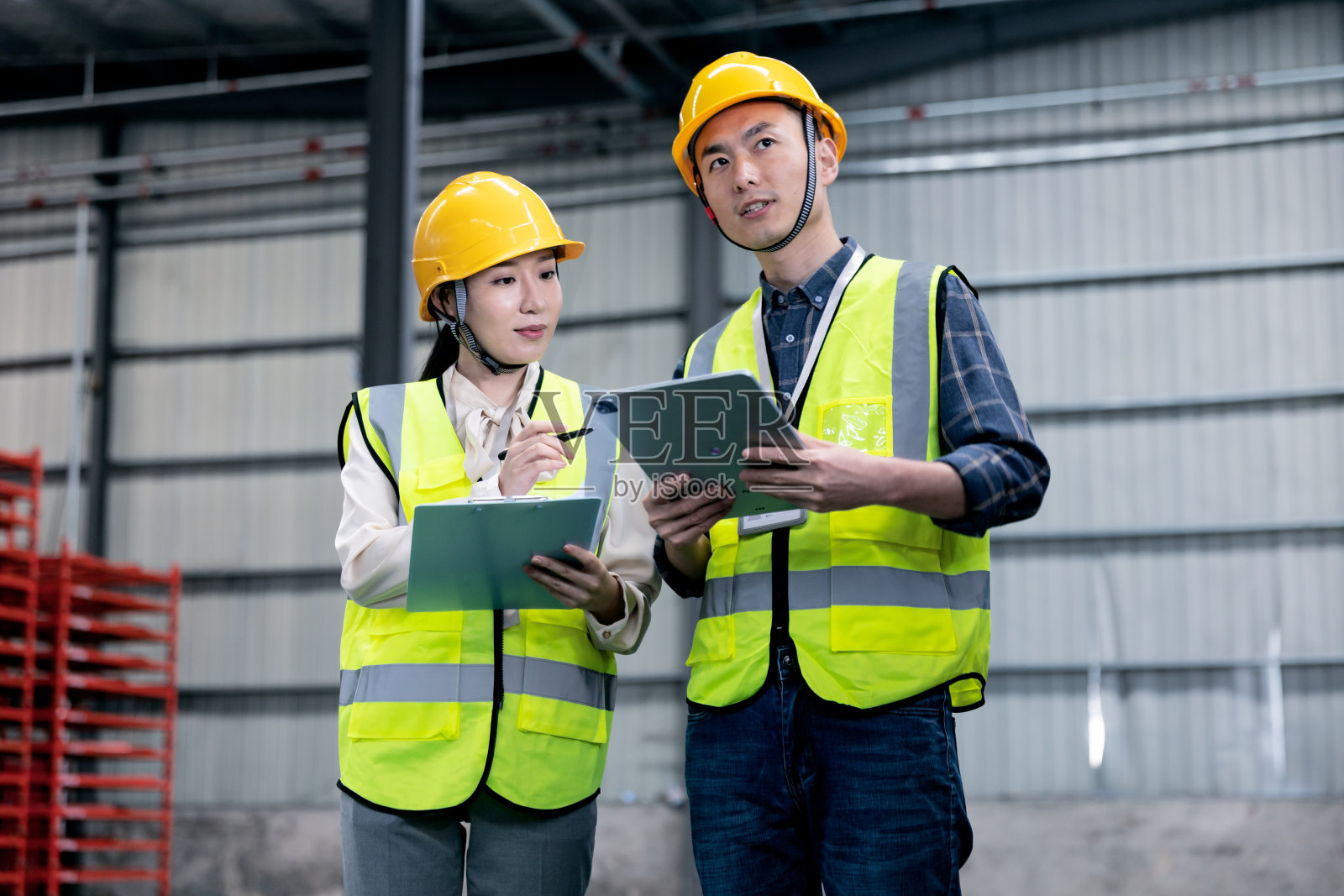 亚洲男性仓库工人在配送仓库货架的过道里与他的团队讨论。照片摄影图片