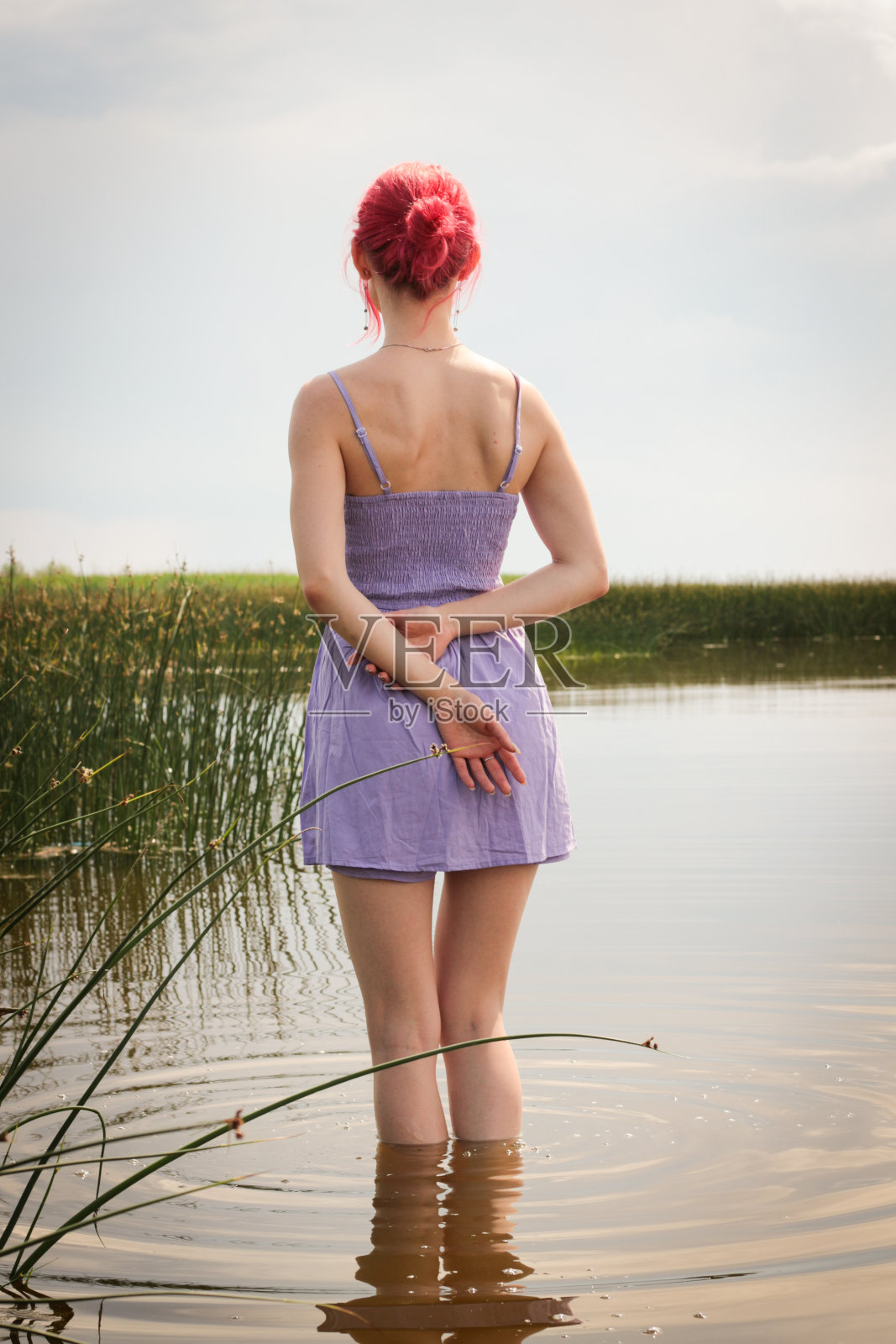 穿着裙子的漂亮女孩在水中以自然为背景摆姿势。高质量照片照片摄影图片