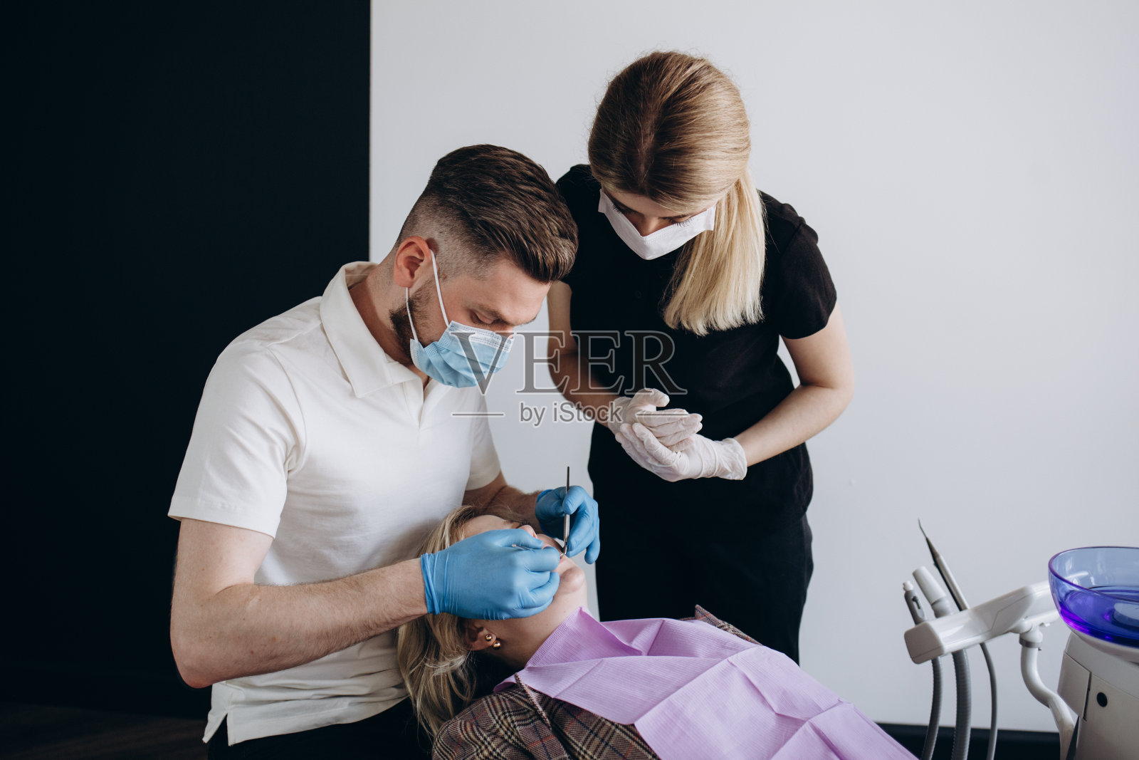 牙医在牙科诊所工作,病人坐在椅子上照片摄影图片