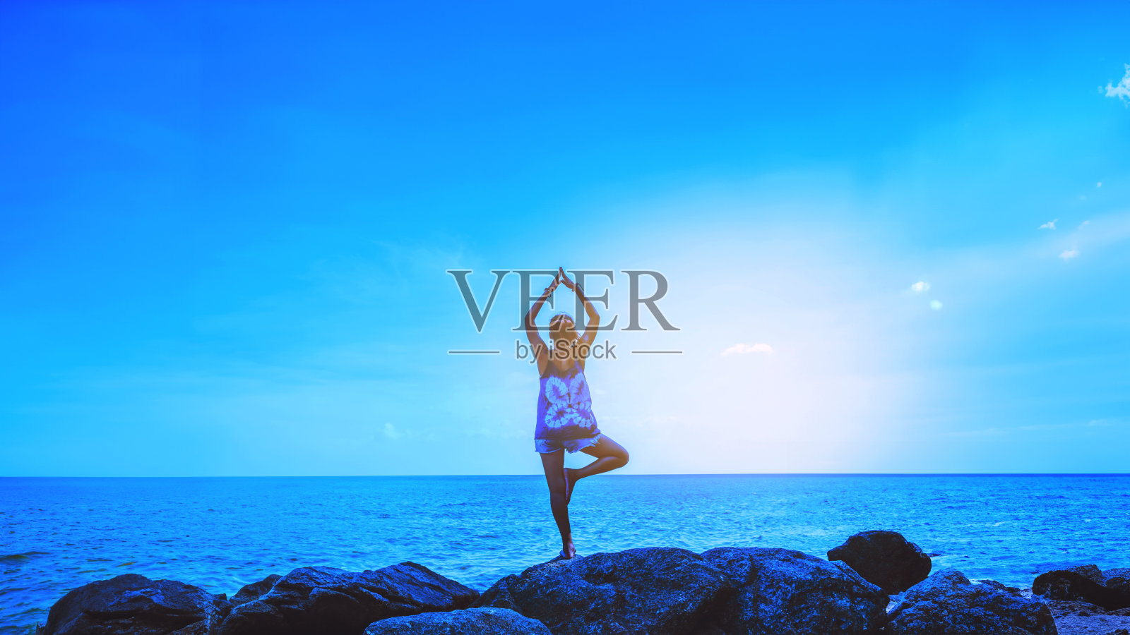 亚洲女性在节日里放松。旅行放松。练习瑜伽。在海边的岩石上。在夏天。泰国照片摄影图片