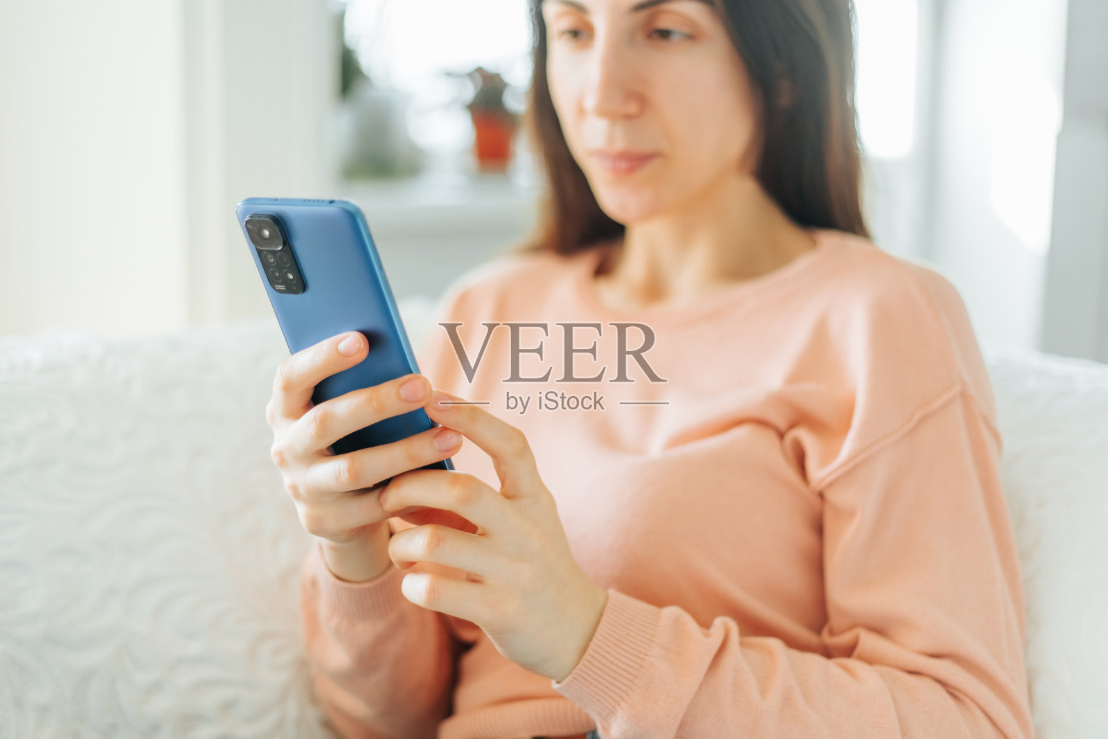 一位年轻女子坐着,拿着她的智能手机,享受着一杯咖啡照片摄影图片