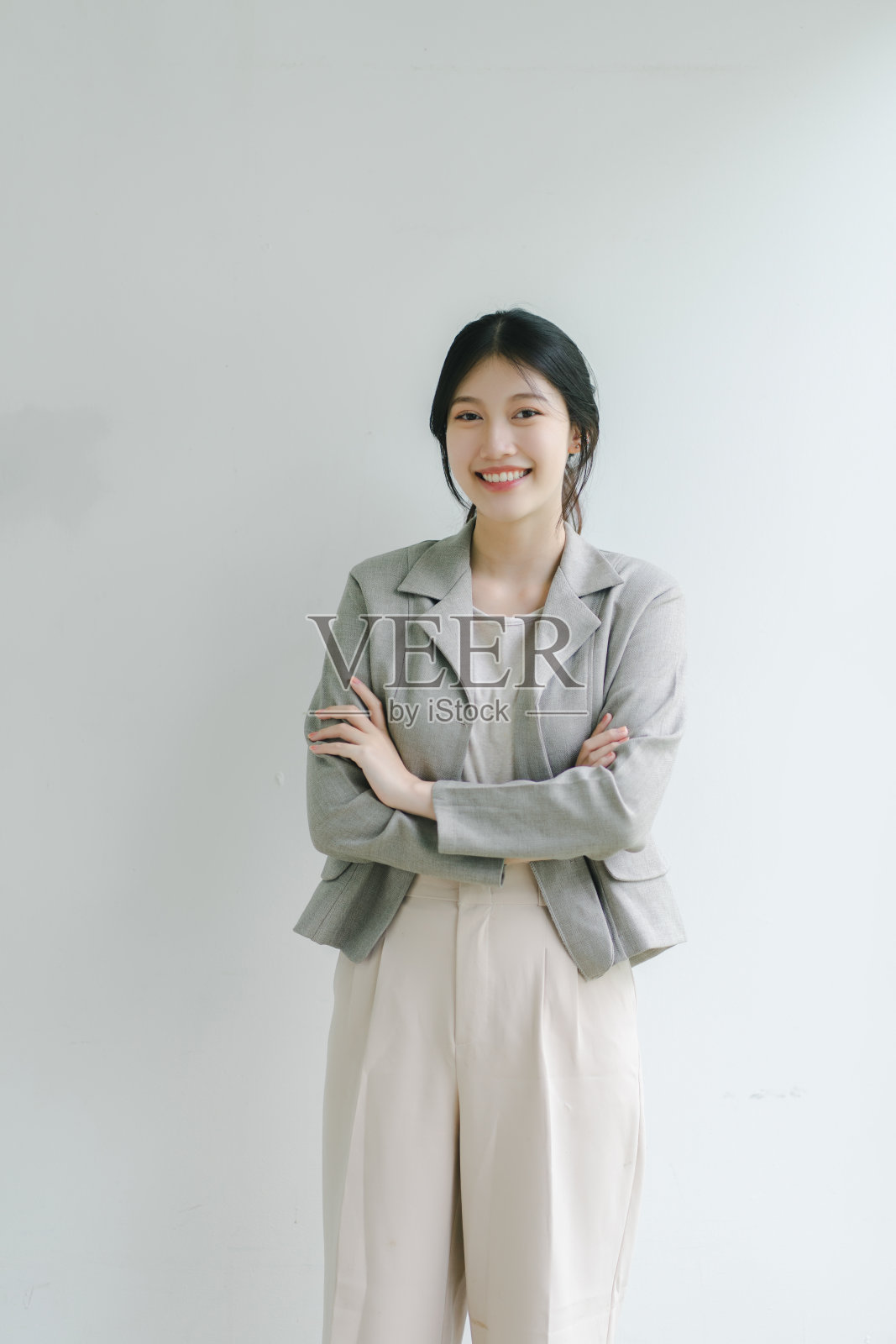 自信的年轻亚洲女商人双臂交叉站在朴素的背景下。照片摄影图片