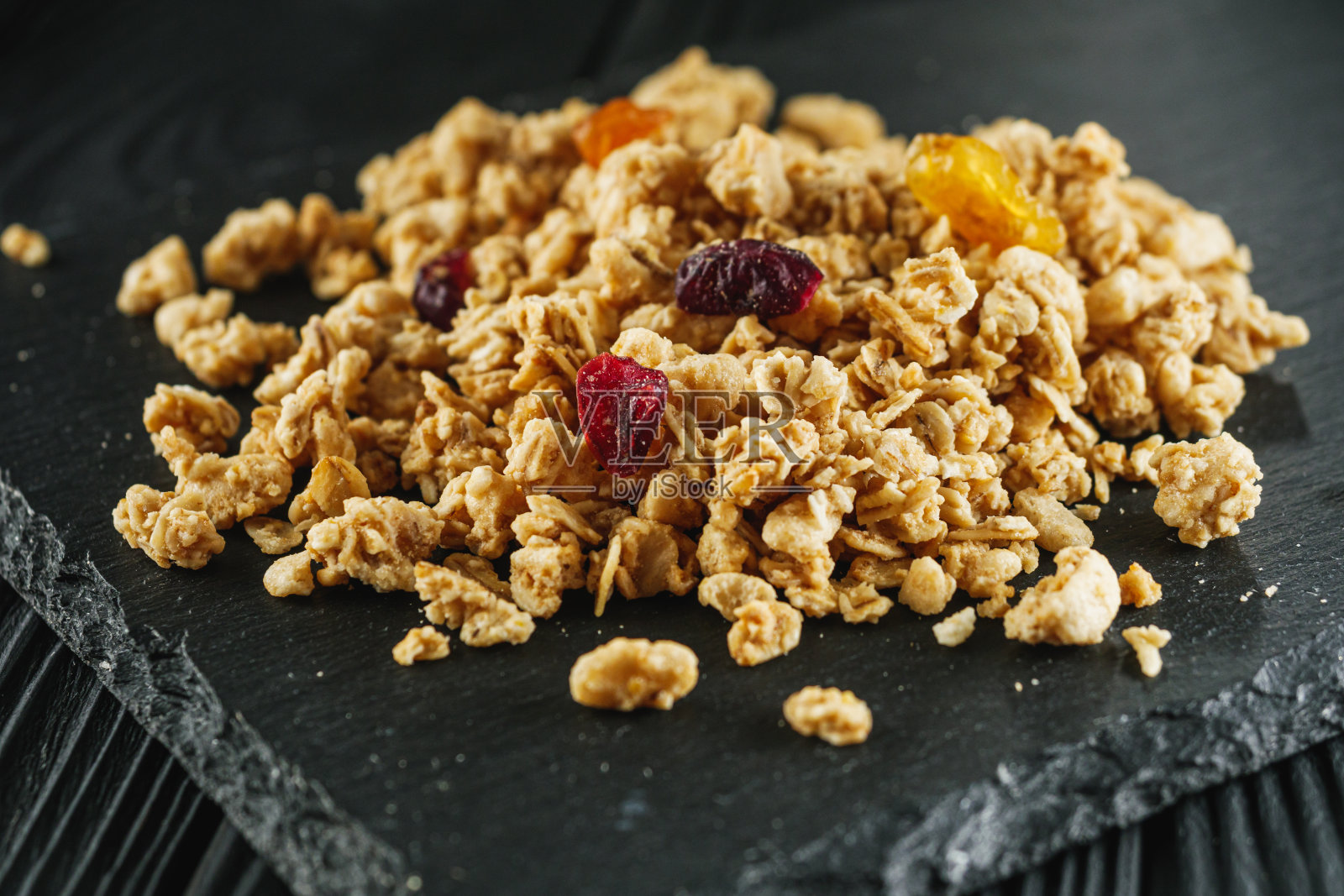 美味脆脆的格兰诺拉麦片配上干果,配上黑色木质乡村背景照片摄影图片